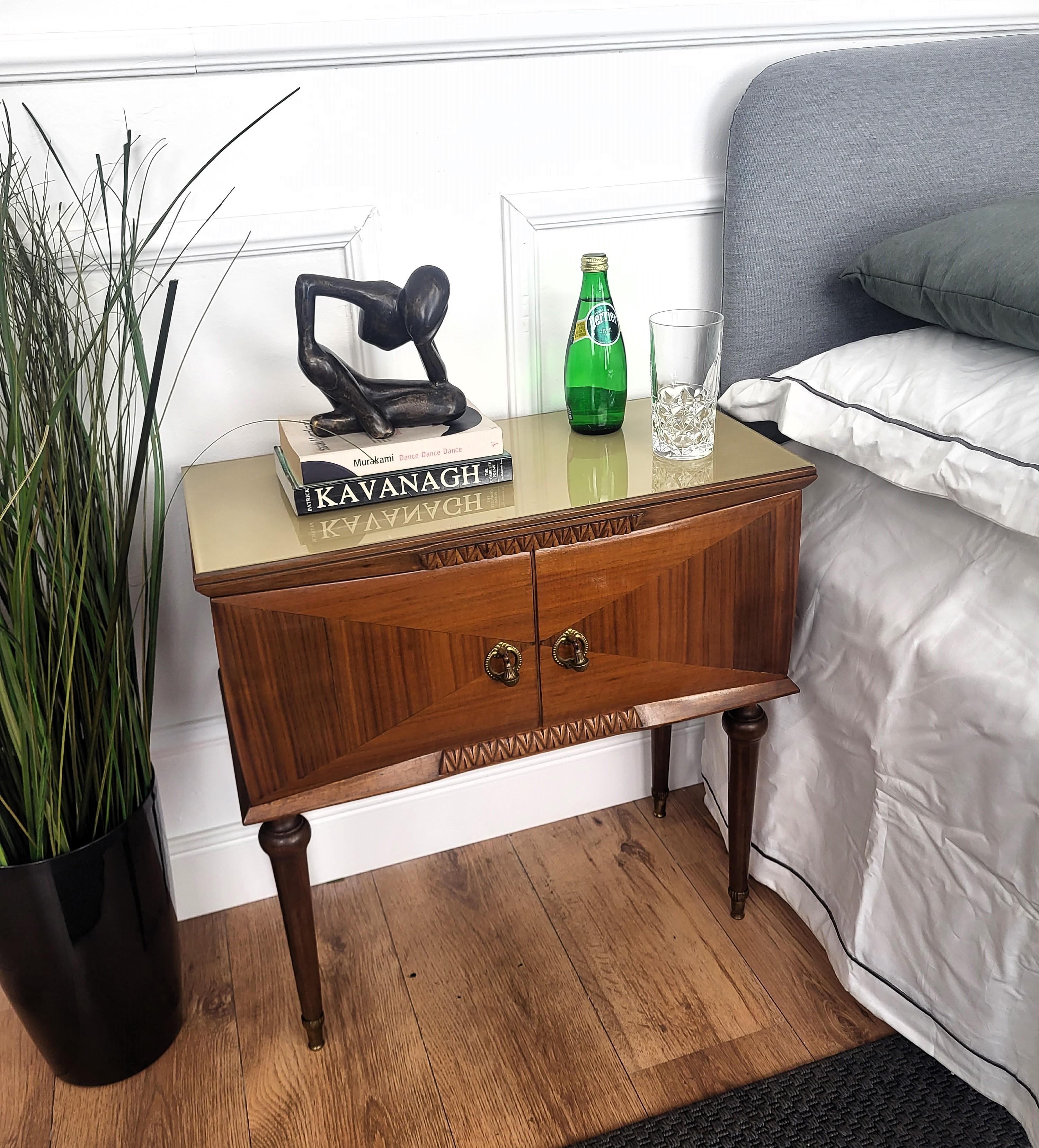 Very elegant and refined Italian 1950s Mid-Century Modern pair of bedside tables with wood double front door, green glass top and wood veneer decors on the sides and doors, and brass details such as the 2 handles and the 4 foot ends. 

Those pieces