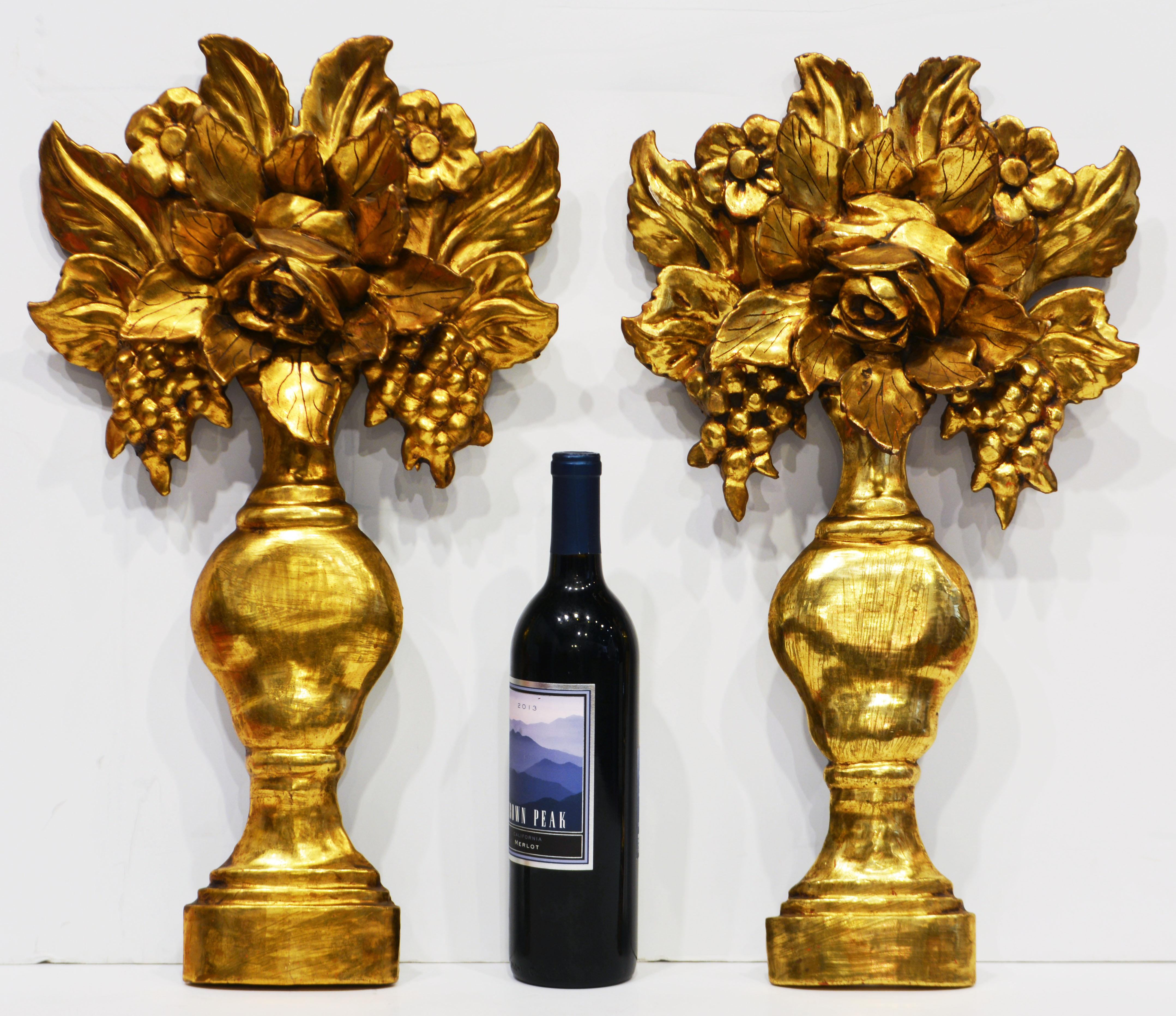 This pair of vintage mid century giltwood wall decorations are carved in the shape of classical urns holding bouquets of flowers, grapes and leaves.