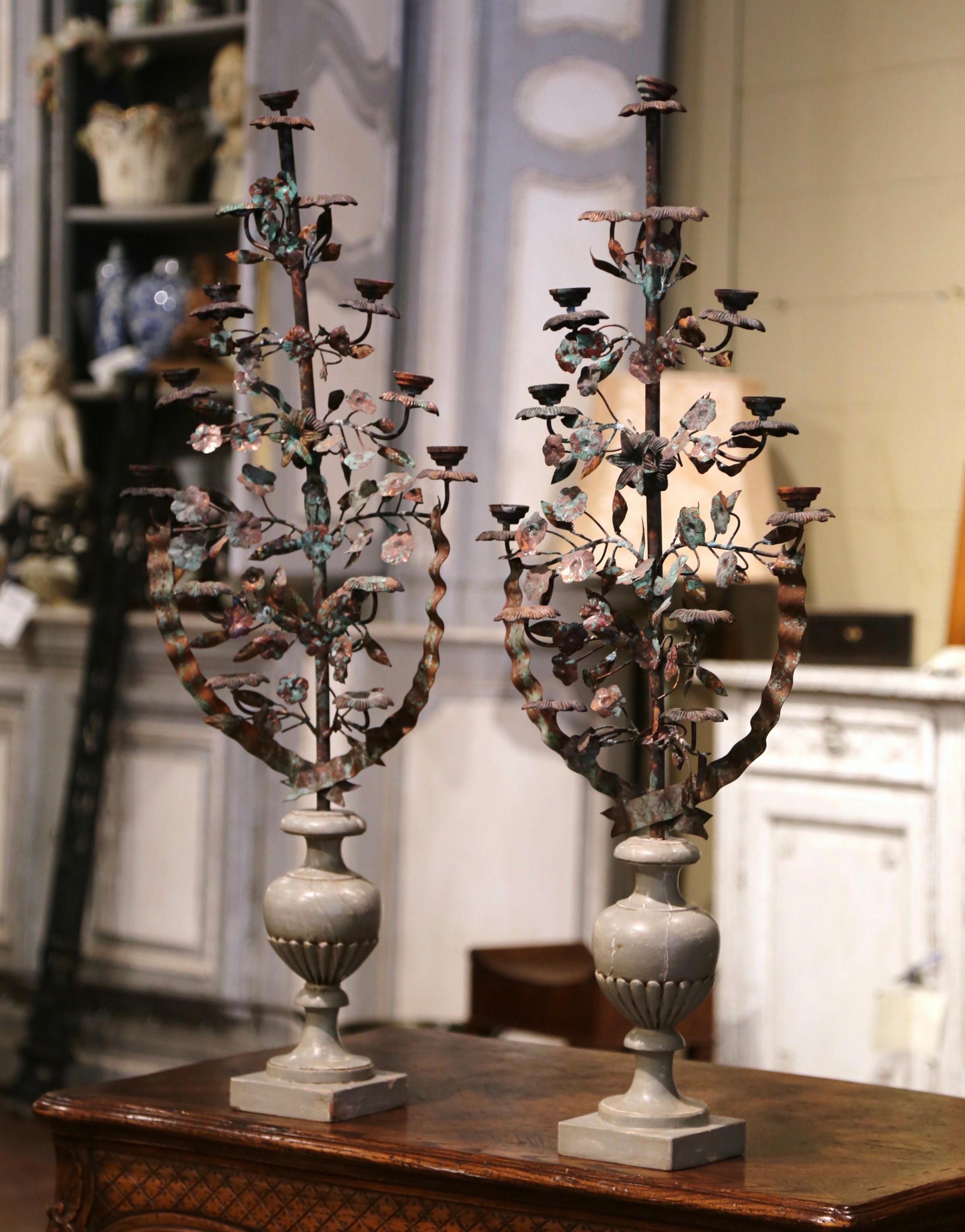 Make an elegant statement in your home with these ornate antique candelabras. Crafted in Italy, circa 1950, each candle holder stands on a urn form base, and decorated with metal flowers and leaves including seven arms to hold candles. The tall