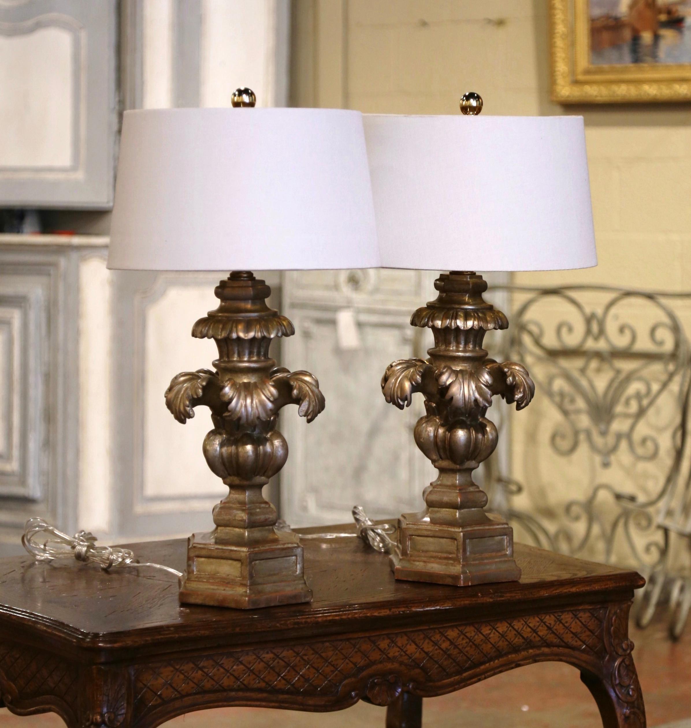 Place these elegant antique lamps on bedside tables or on top of a console in an entry! Crafted in Italy circa 1970, each lamp sits on a polygon bottom over an urn form base, decorated with hand carved acanthus leaf motifs throughout. Both lamps
