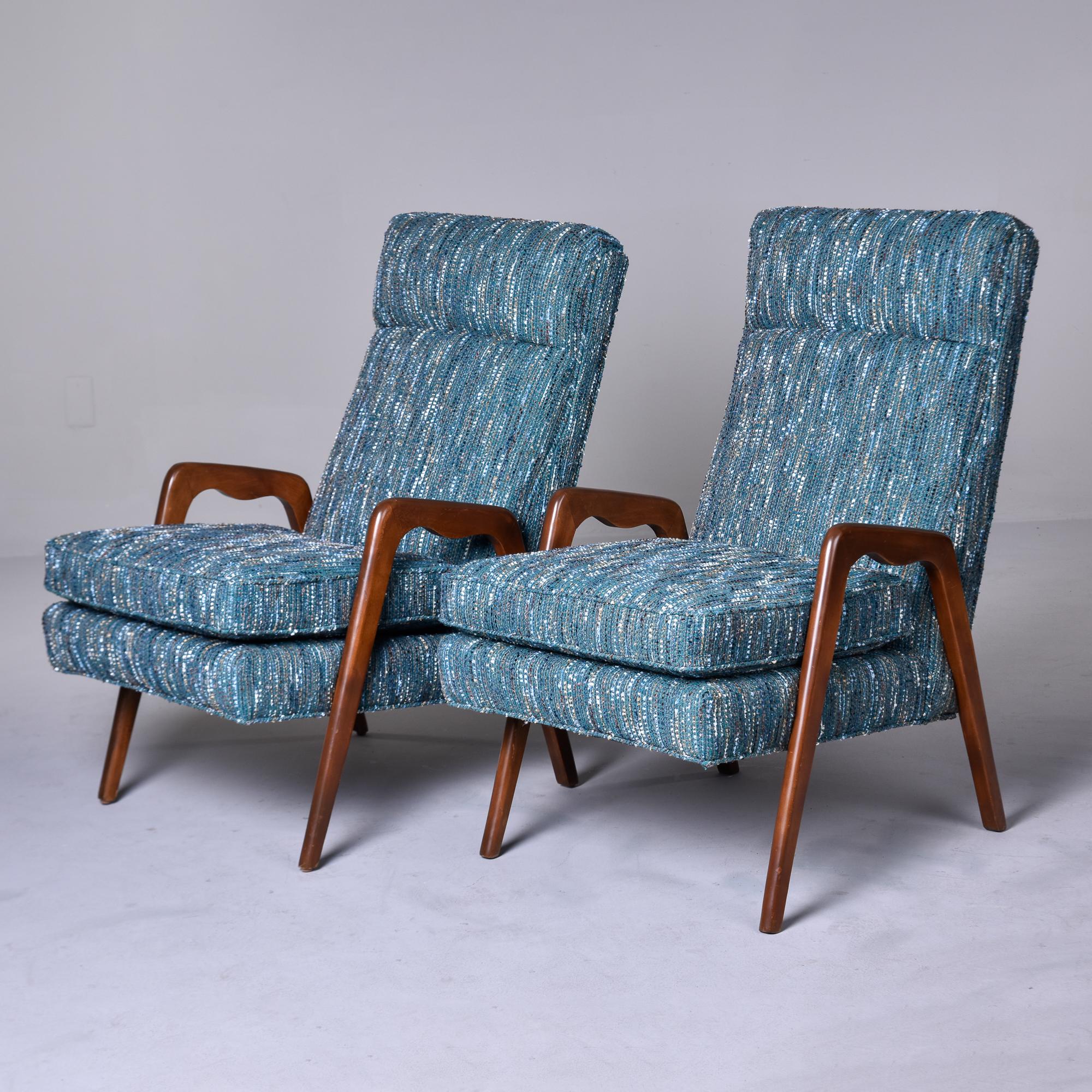 Found in Italy, this pair of circa late 1950s/early 1960s arm chairs have sleek, tapered dark stained wood arms and legs. Tall, slanted seat backs have a seamed headrest. Chairs are newly upholstered in a nubby teal blue cotton blend woven tweed