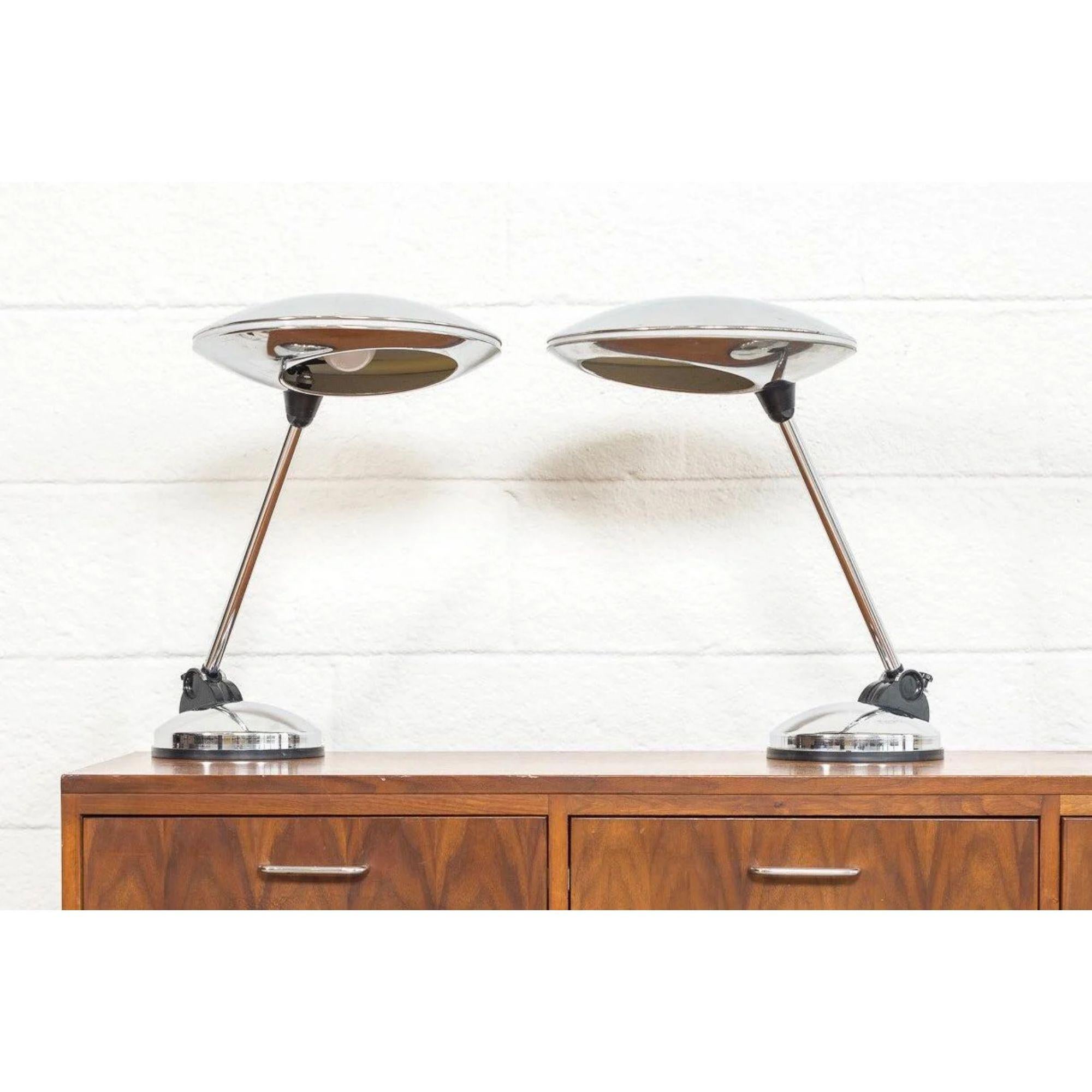 This pair of vintage Mid-Century Modern articulating table desk lamps were made in Italy, circa 1960. The unique, modernist design features distinctive saucer-shaped polished chrome shades with a translucent stripe in center which illuminates when