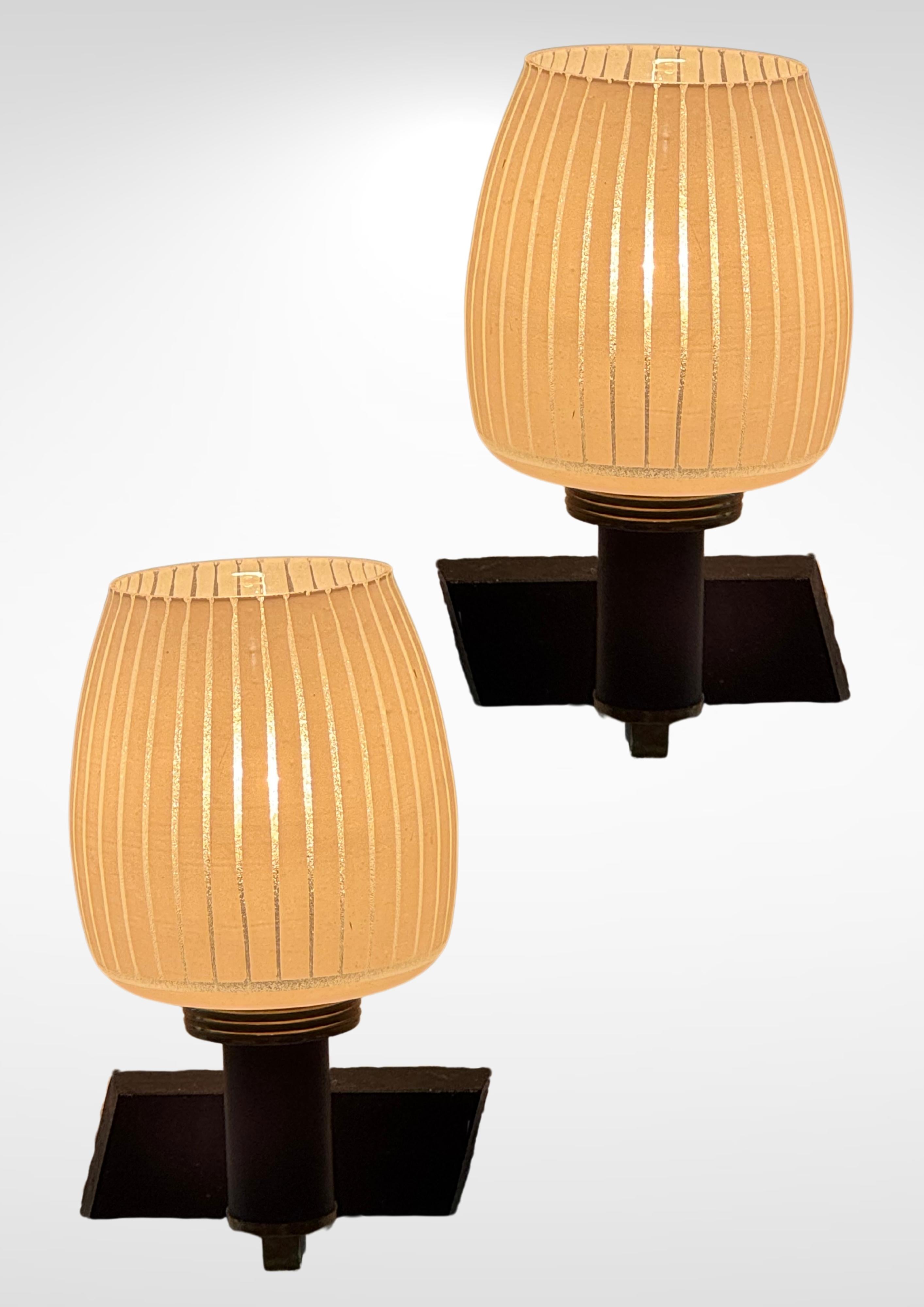 Coppia di appliques in vetro smerigliato di design italiano degli anni '50 alla maniera di Stilnovo.
Realizzato con componenti in metallo di ottone e staffe da parete in ferro battuto.
I diffusori sono realizzati in vetro smerigliato con linee