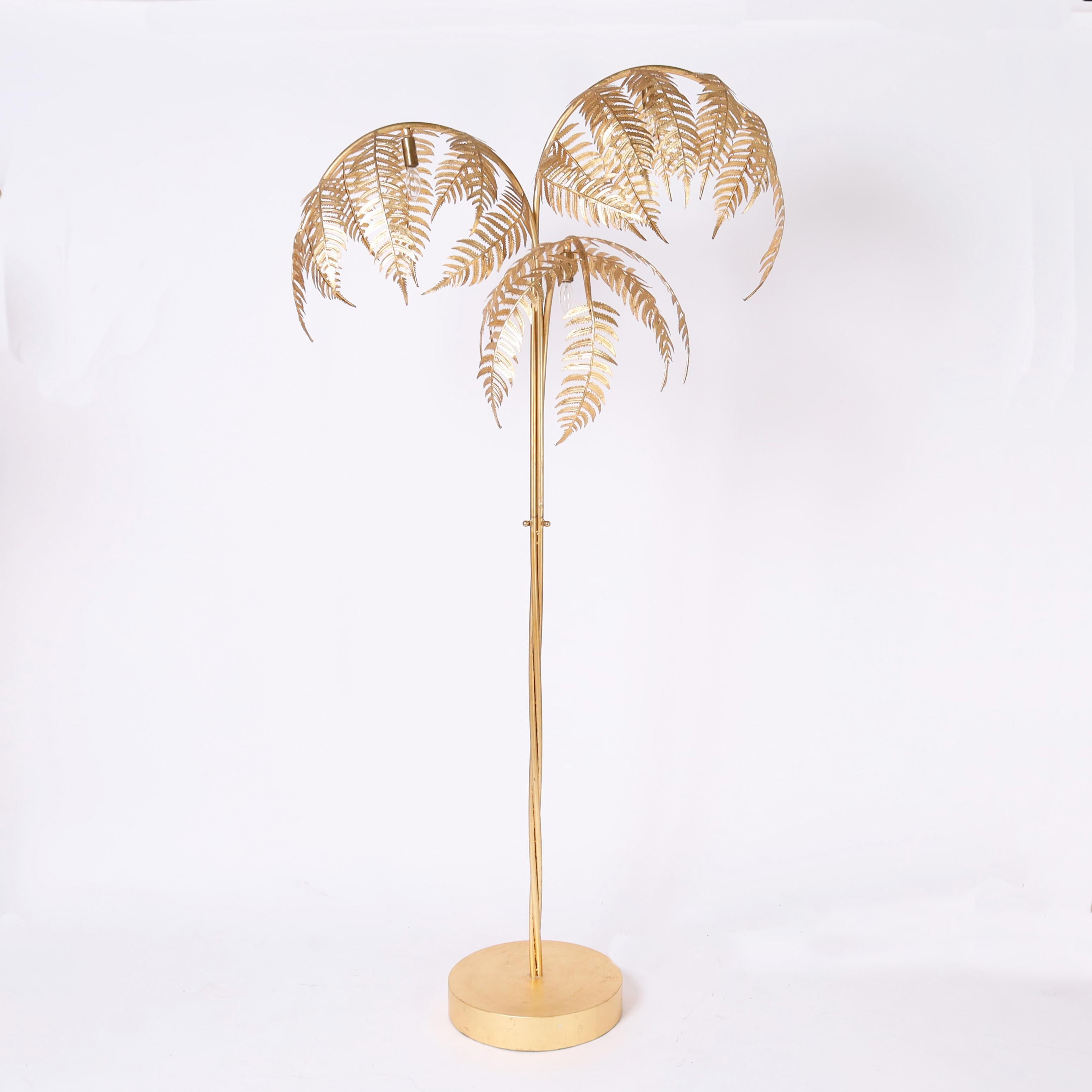 In vogue pair of vintage Italian floor lamps crafted in metal with a gilt finish in a stylized palm tree form with three leaves, three lights, three twisted stems and a round base with a foot switch. 