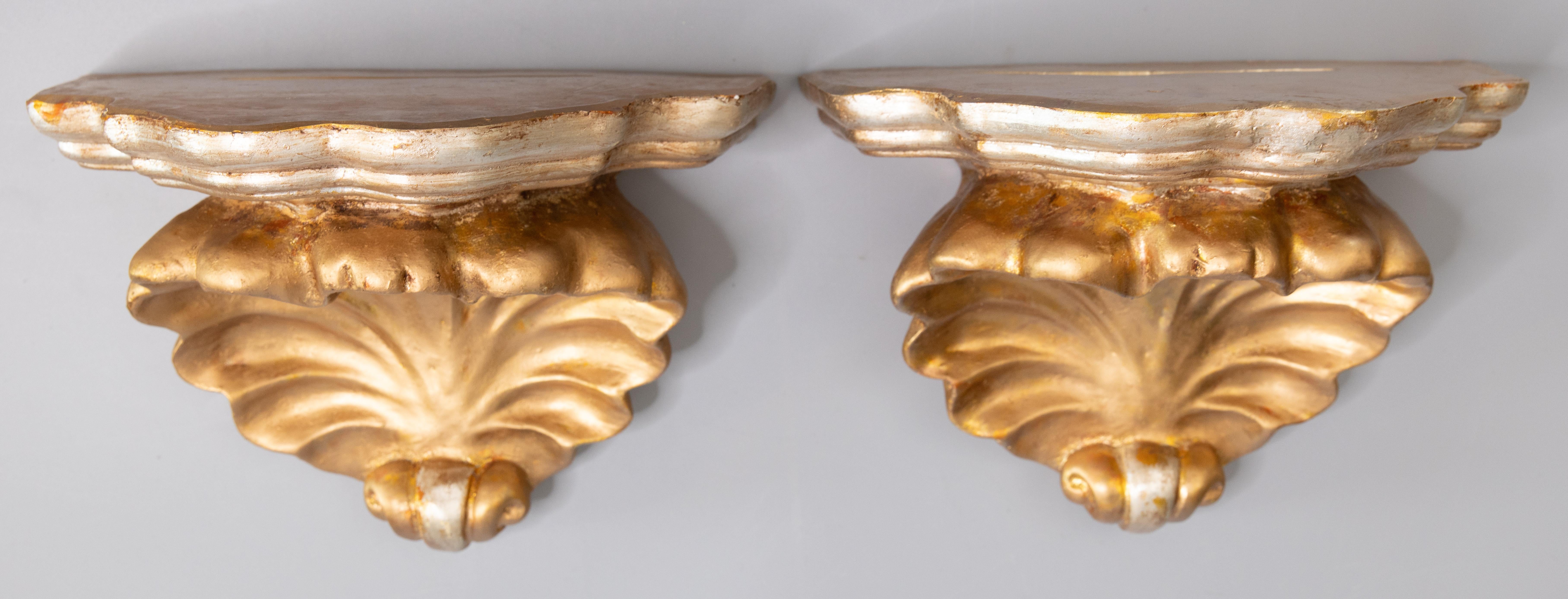 A lovely pair of vintage Mid-Century Italian gilded plaster wall brackets or shelves with a seashell design and silver accents. They are perfect for displaying decorative collectibles or fabulous on their own.

DIMENSIONS
10.75ʺW × 6.25ʺD × 7.5ʺH