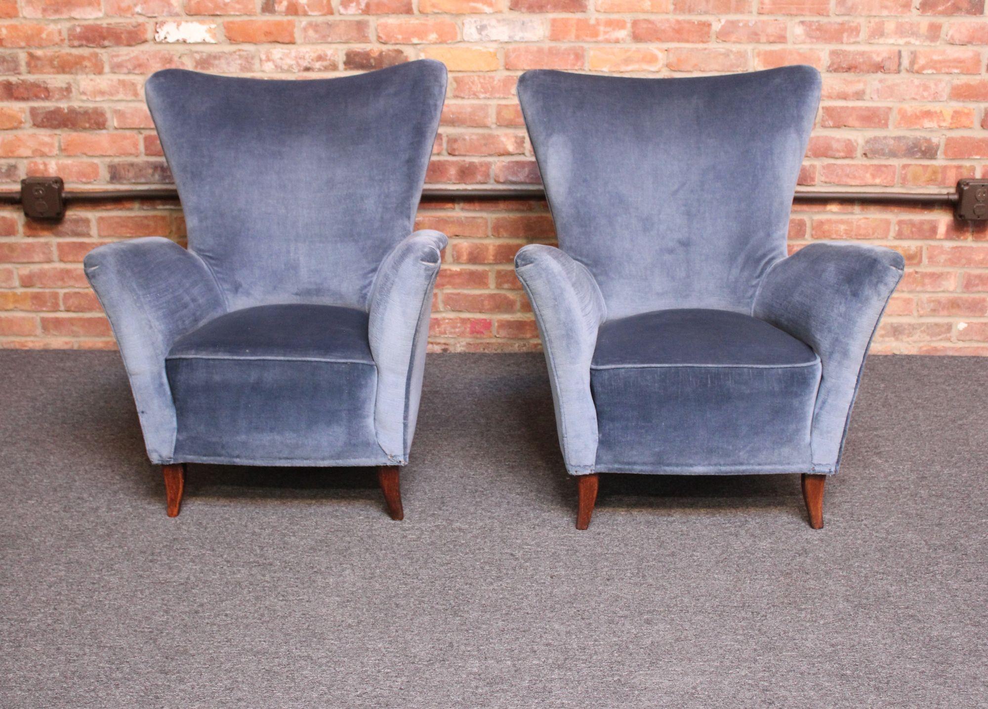 Pair of Italian modern lounge chairs with elegant, sweeping lines and subtle high, wing-back form supported by delicately curved stained mahogany legs (ca. 1950s, Italy).
Dramatic, deeply sculpted armrests show well from all angles, adding sharp