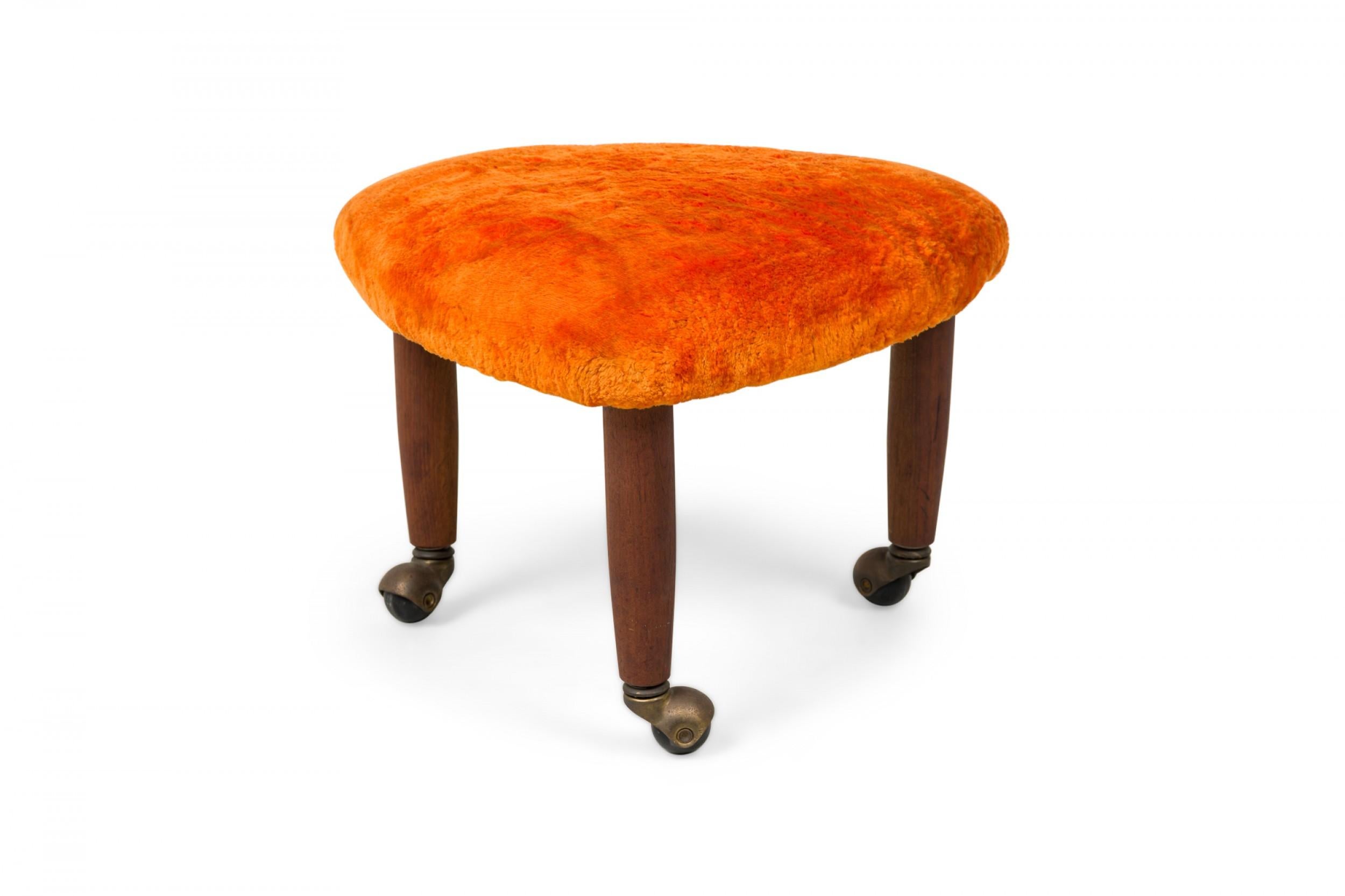 PAIR of midcentury Italian Modern triangular footstools, upholstered in plush orange velour, standing on 3 legs with brass casters. (manner of Gio Ponti) (PRICED AS PAIR)(Available in black: REG4086A).