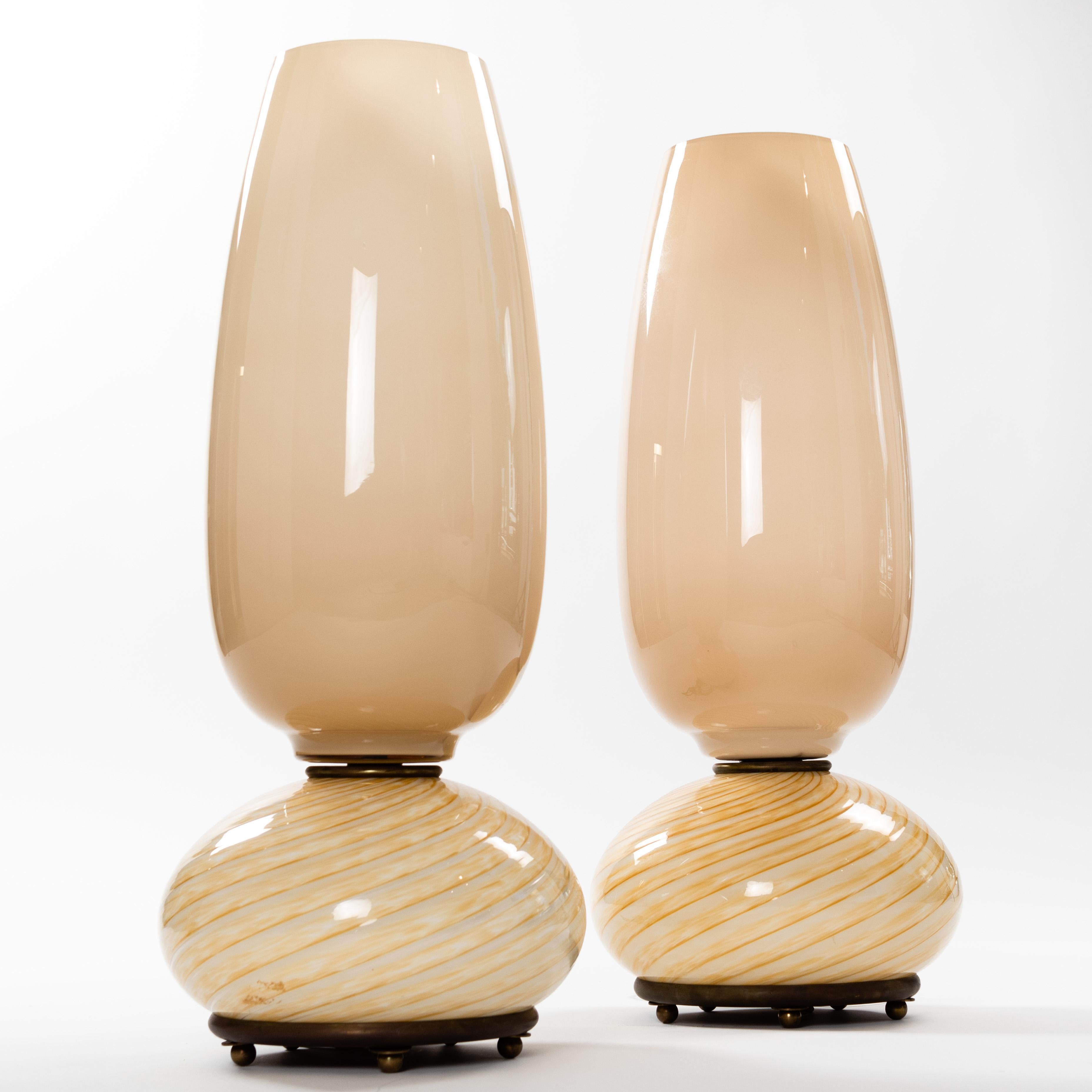 A wonderful and rare pair of Venini table lamps from the late 1970s.
Delicate camel-colored Murano glass give the objects a soft tone. 
The spiral glass base rests on a bronze plate with small bronze feet. The interior of the screen is off-white