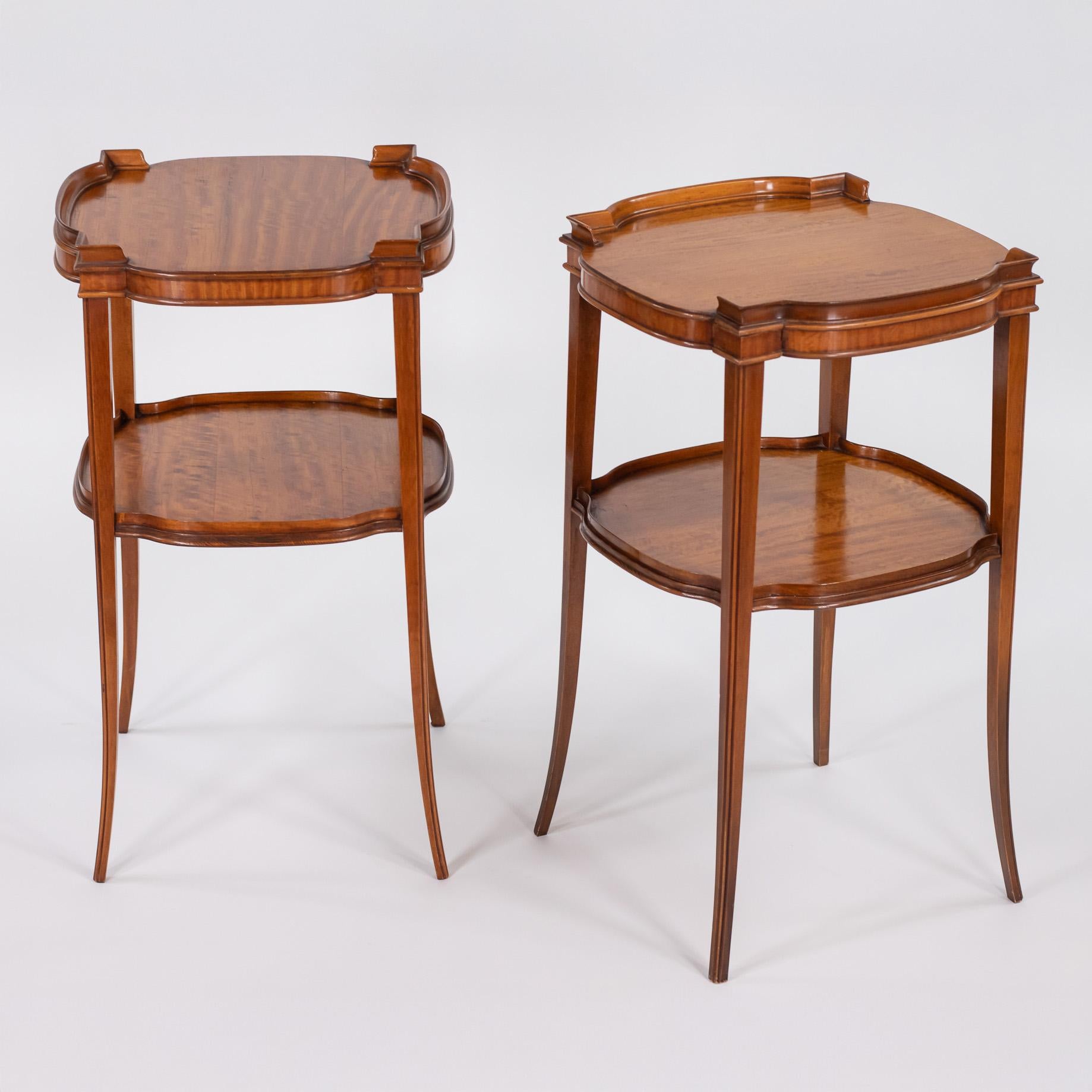 A pair of Mid-Century Italian satinwood veneered end tables, circa 1950s-1960s. Pine construction with satinwood veneer displaying prominent cathedral grain patterns. Two-tier design with cartouche-shaped top and eared (crossetted) corners, molded