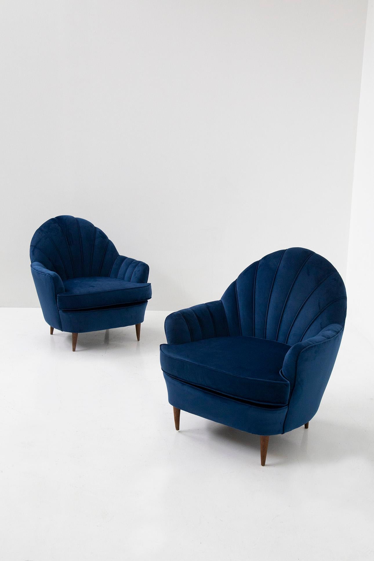 Elegant pair of 1950s Italian armchairs. The pair of armchairs feature a shell design typical of the Italian midcentury. The armchairs have recently been refreshed in an elegant blue velvet. Their most prominent feature is their shell-shaped
