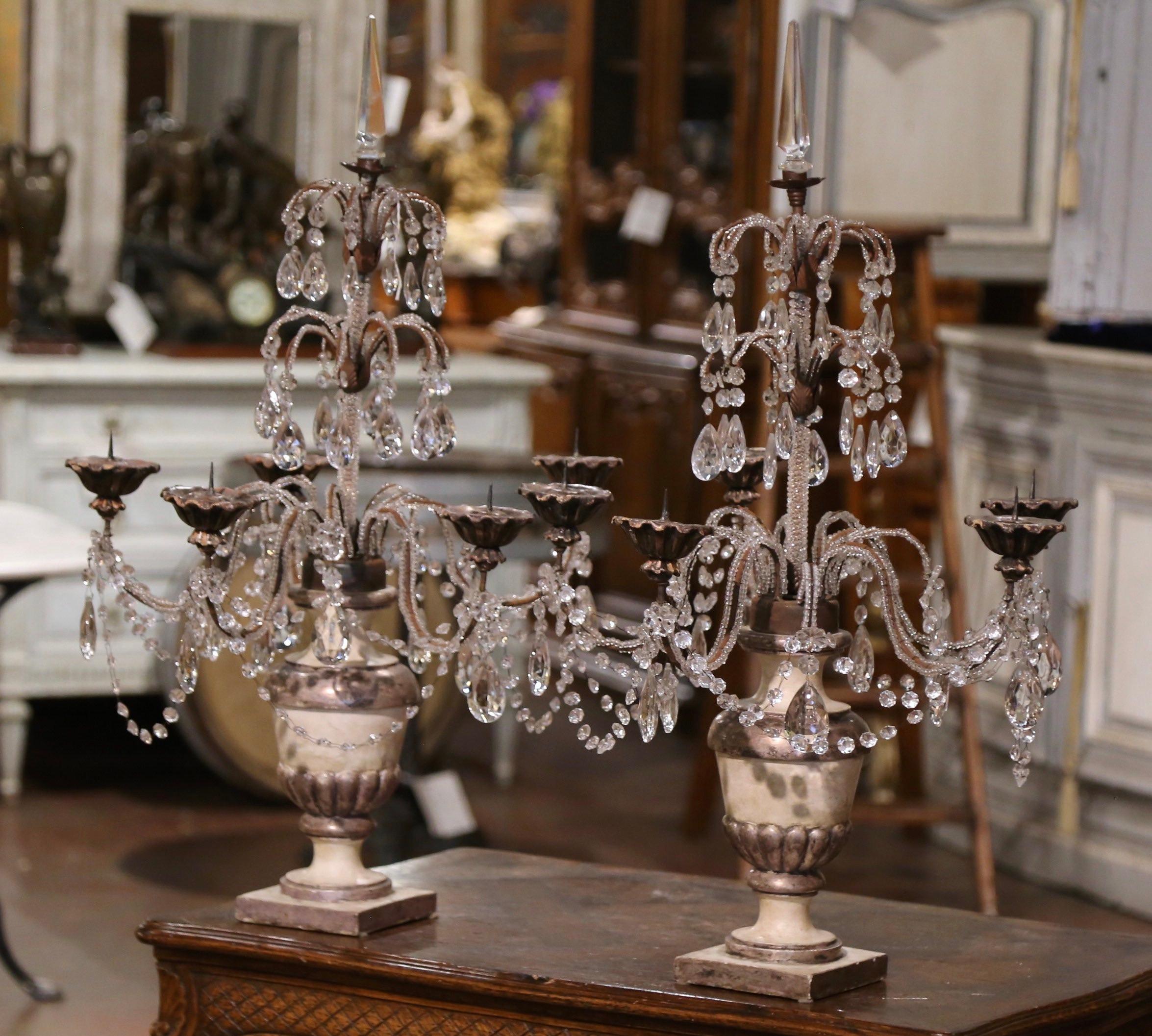 Decorate a buffet or console with this elegant pair of colorful girandolles. Crafted in Italy circa 1960, each candelabra stands on an inaugural carved vase shaped base; the vase is hand painted in beige with silver leaf and some gilt accents
