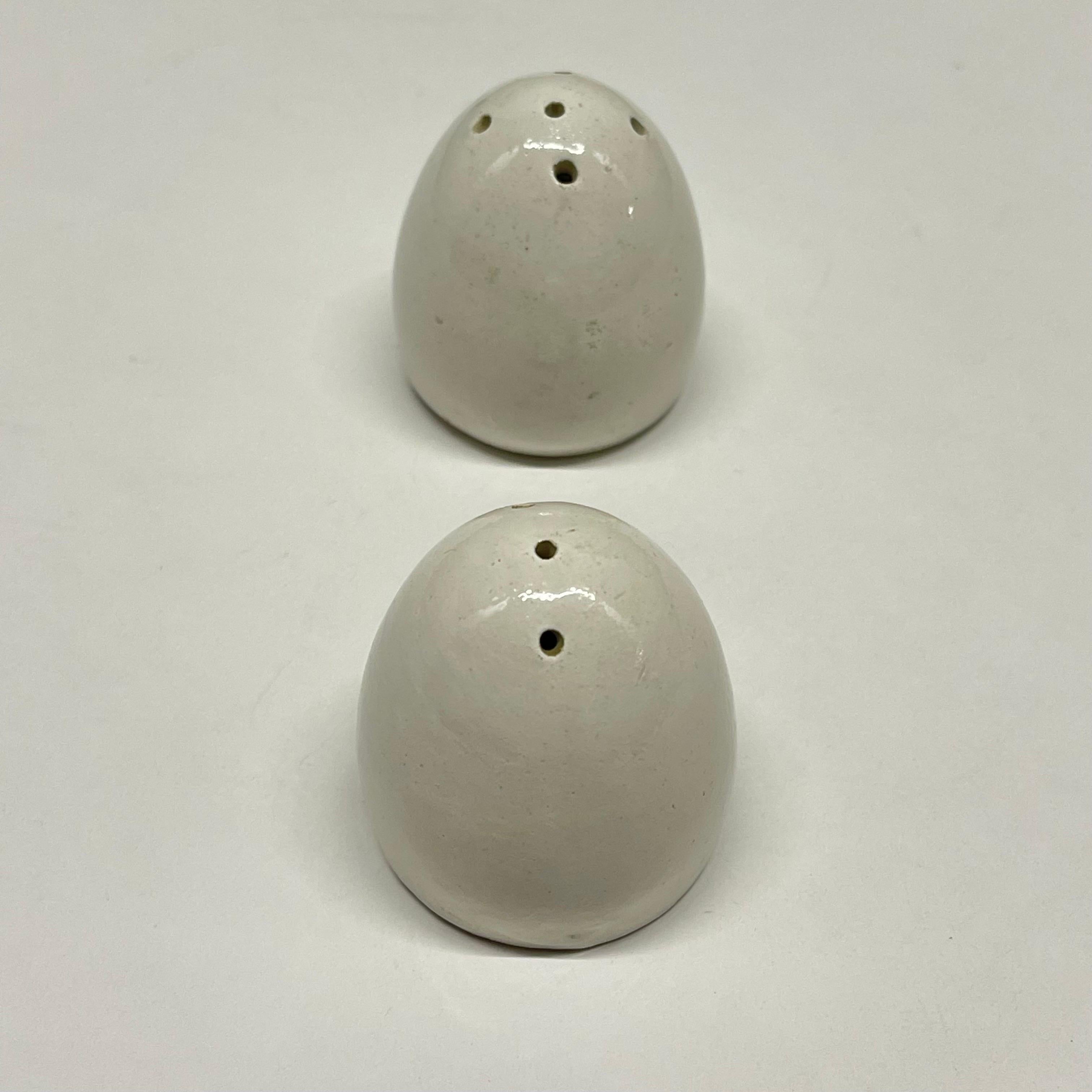 Surrealist pair of Mid-Century Modern Italian salt and pepper shakers in the form of two eggs. Rendered in white glazed ceramic pottery with cork stoppers. Signed and made in Italy, circa 1960s.