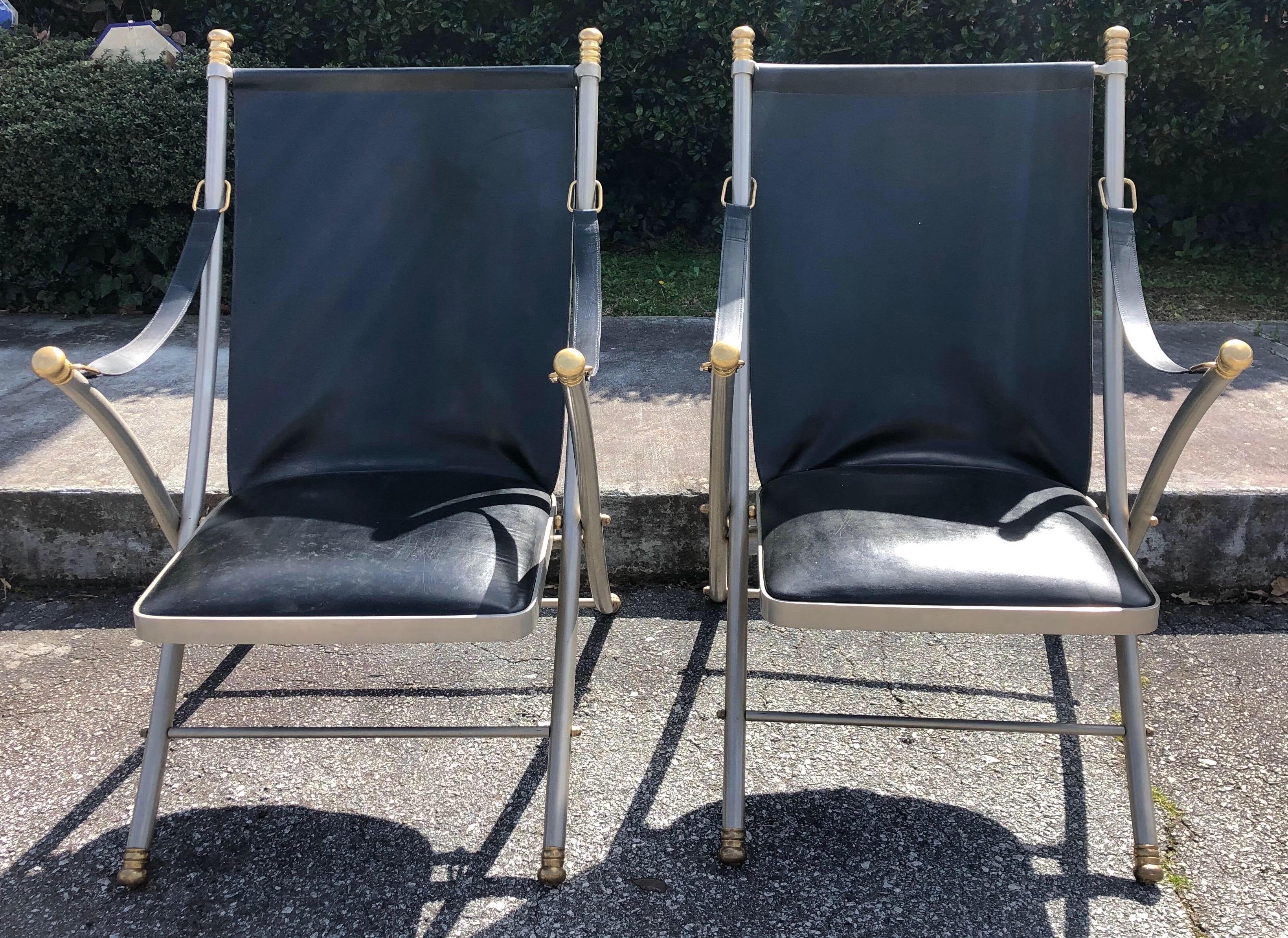 Pair of midcentury Jansen Campaign chairs in steel, leather, and brass. Great black leather seats and straps set in polished steel with brass feet and caps.