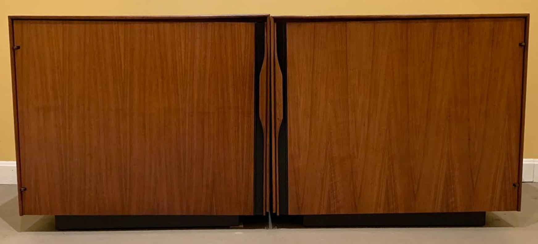 A fine pair of walnut single door side tables or nightstands with a white Formica slide out shelf on each, as well as a single interior shelf, designed by John Kapel for Glenn of California, circa 1960s. Glenn of California was a furniture company