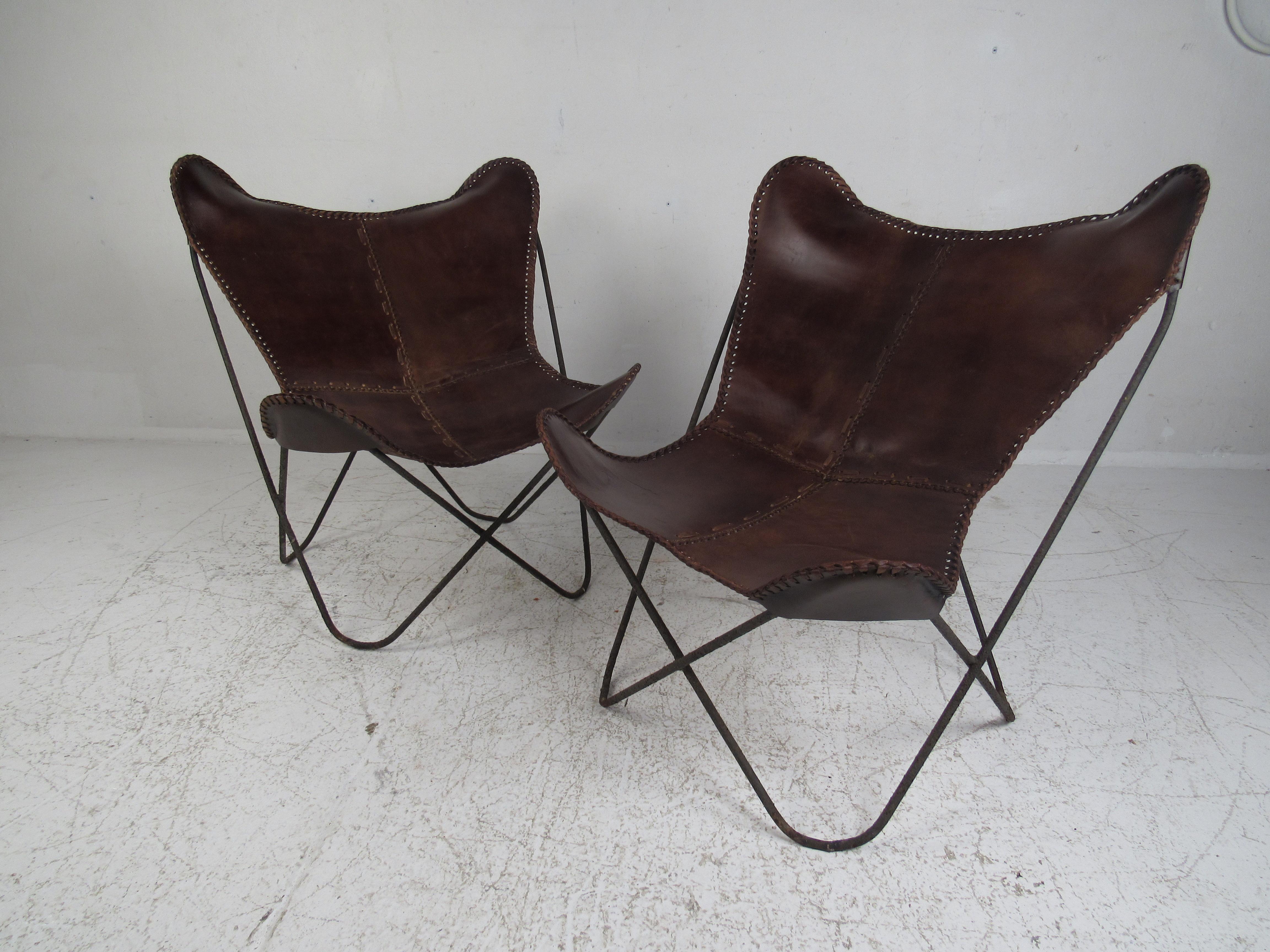 This stunning vintage modern pair of lounge chairs boast a heavy metal frame with hairpin legs and a thick brown leather sling seat. A very unique and sturdy pair of chairs that are sure to make a lasting impression in any seating arrangement. The