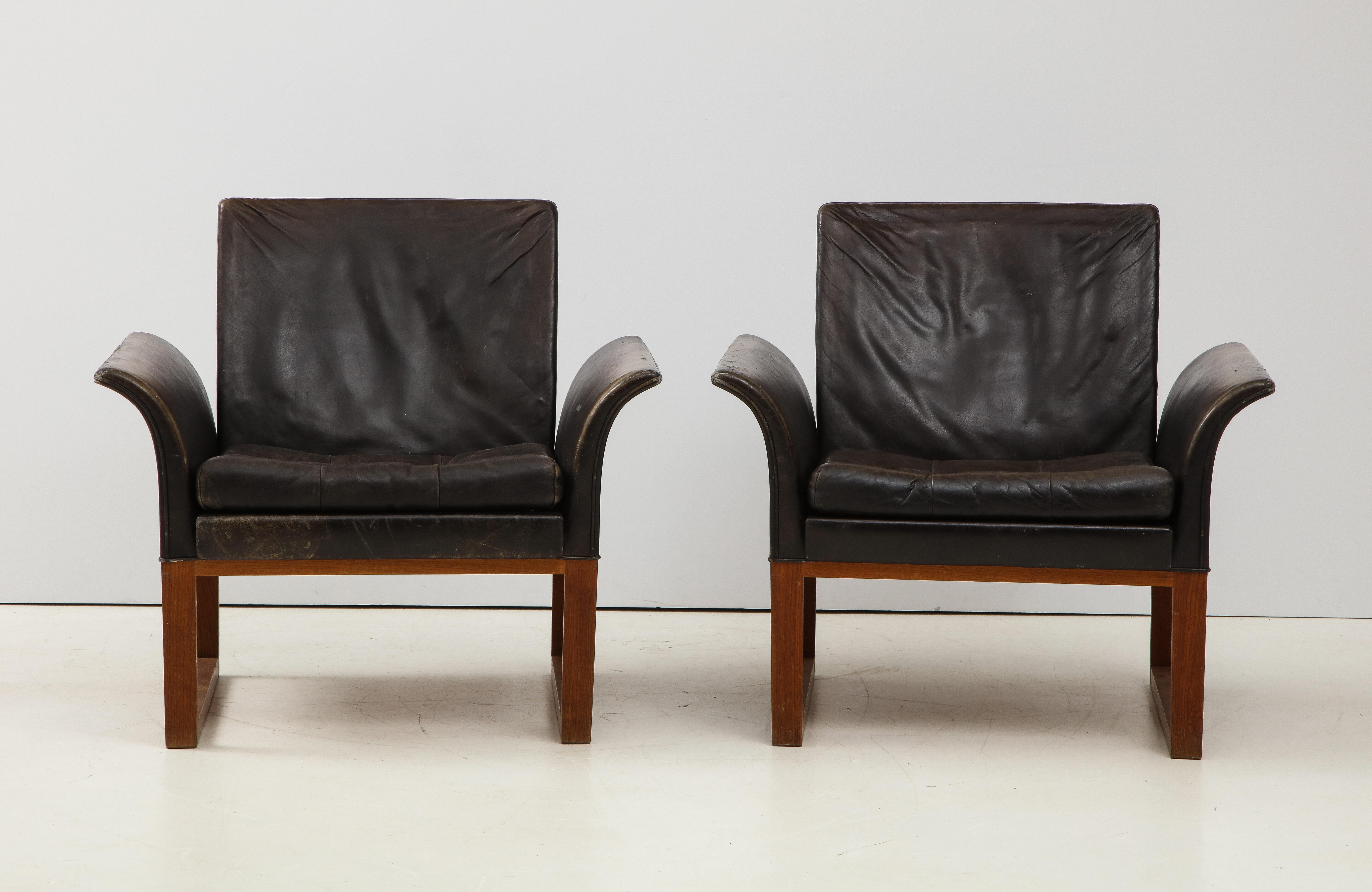 Pair of rare mid-century leather club chairs, Sweden, circa 1950s. 

Excellent construction includes clean U-shaped wood legs, button-tufted leather seat cushions, and an elegant curvature in the arms. Gorgeous patina on the leather, which is