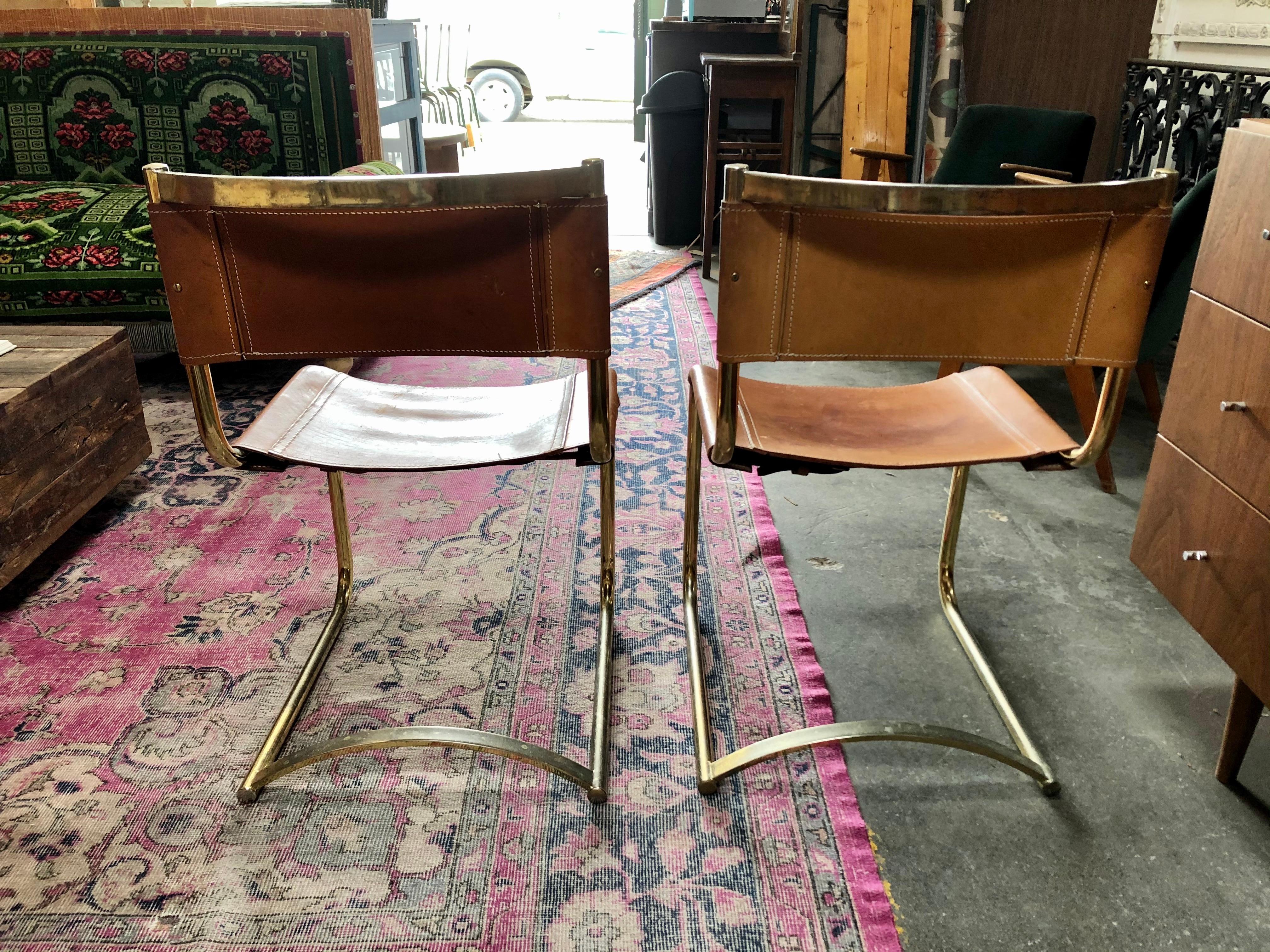 This set of two vintage leather chairs feature gold frames.