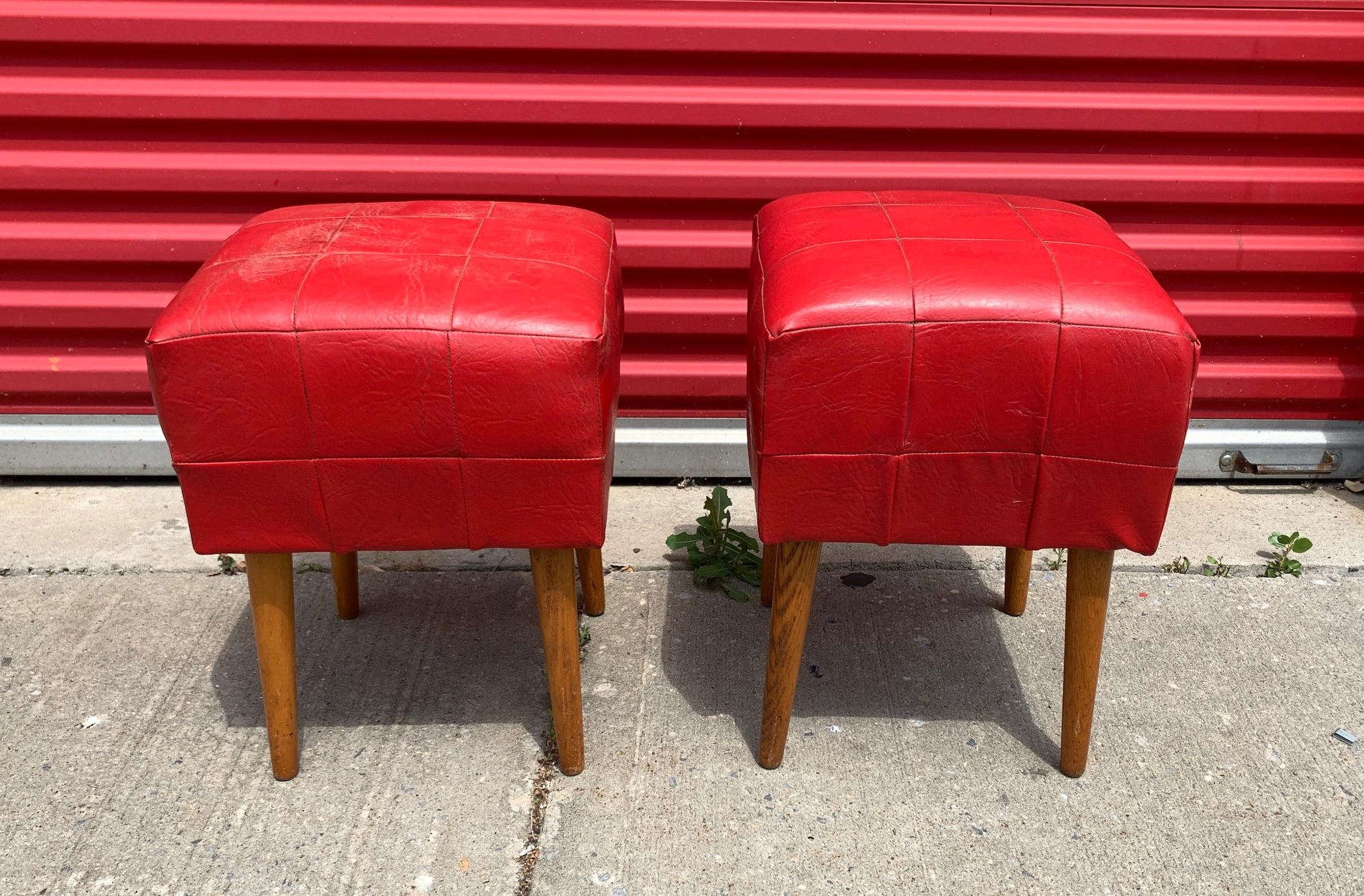 This pair of vivid red midcentury leather ottomans if the perfect pop of color. A great height to lay your tired feet or sit while entertaining. Durable leather that with stand the ages and will hold for more years to come.