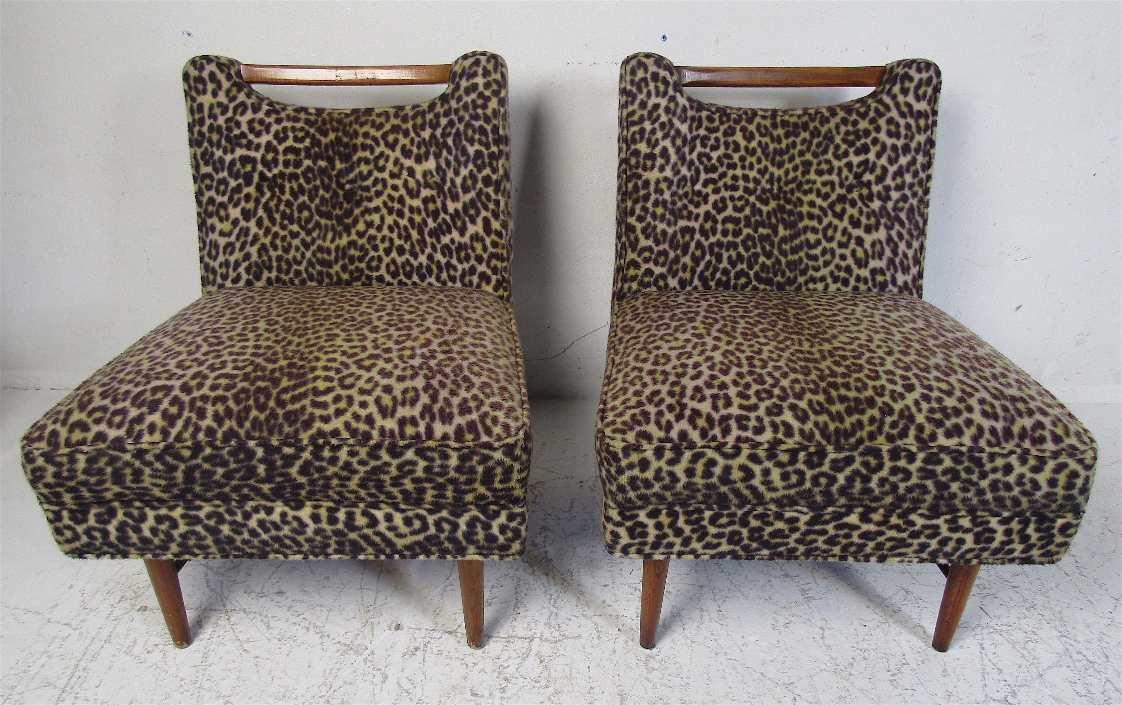 This beautiful pair of vintage lounge chairs feature plush leopard print upholstery and walnut legs. A uniquely designed backrest that features a wood top with a cutout space underneath. This lovely feature also provides a convenient way to move