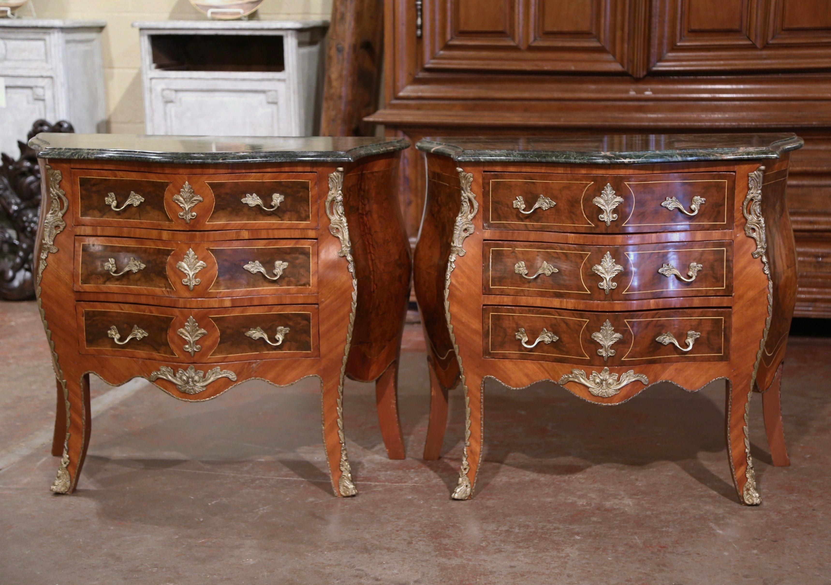 These elegant three-drawer bedside tables were created in France, circa 1950. Bombe in shape on all three sides, each chests stands on cabriole legs ending with bronze sabot feet over a scalloped apron embellished with a brass mount; the sides with