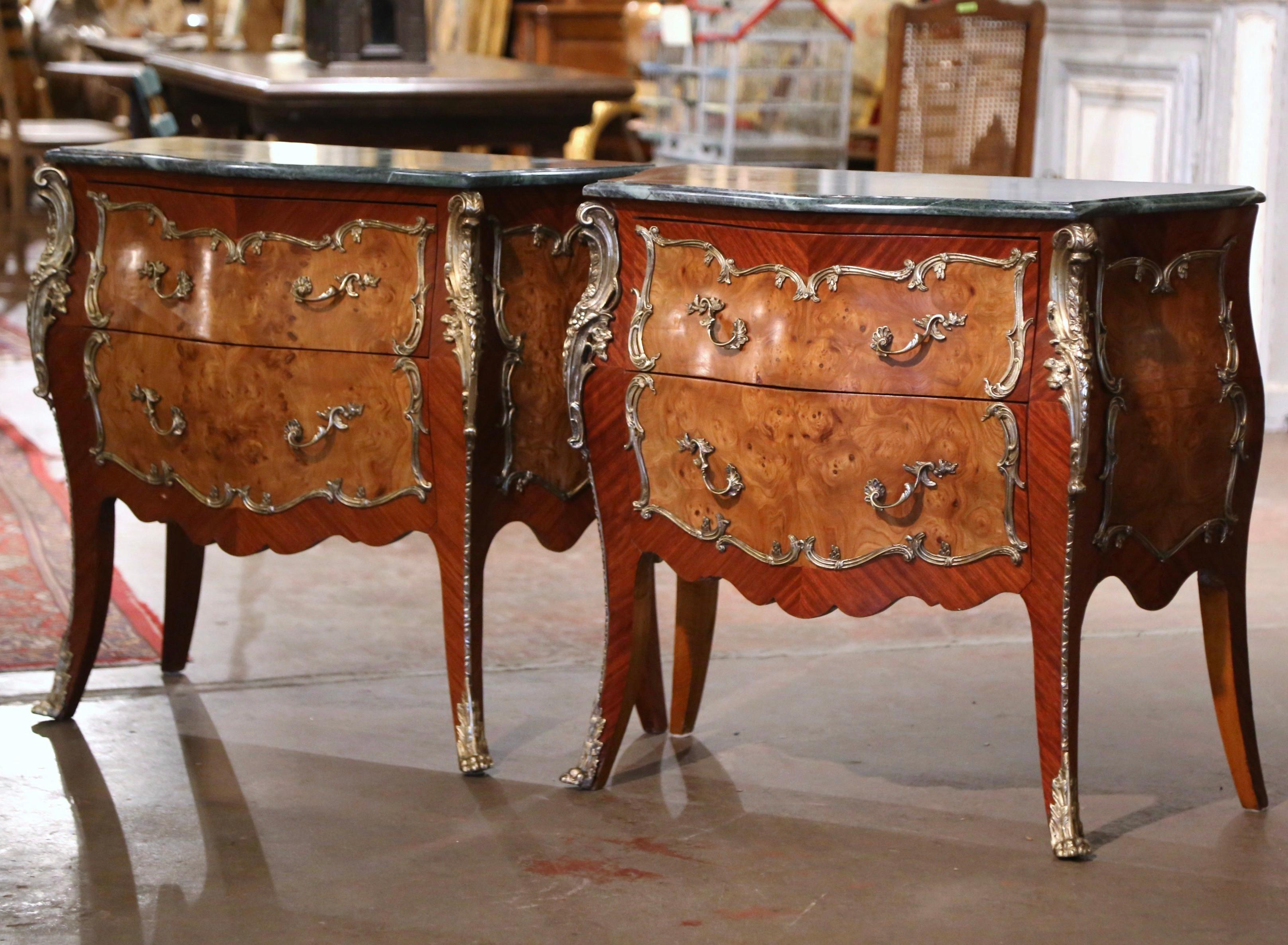 These elegant two-drawer bedside tables were created in France, circa 1950. Bombe in shape on all three sides, each chests stands on cabriole legs ending with bronze sabot feet over a scalloped apron embellished with a brass mount; the sides with