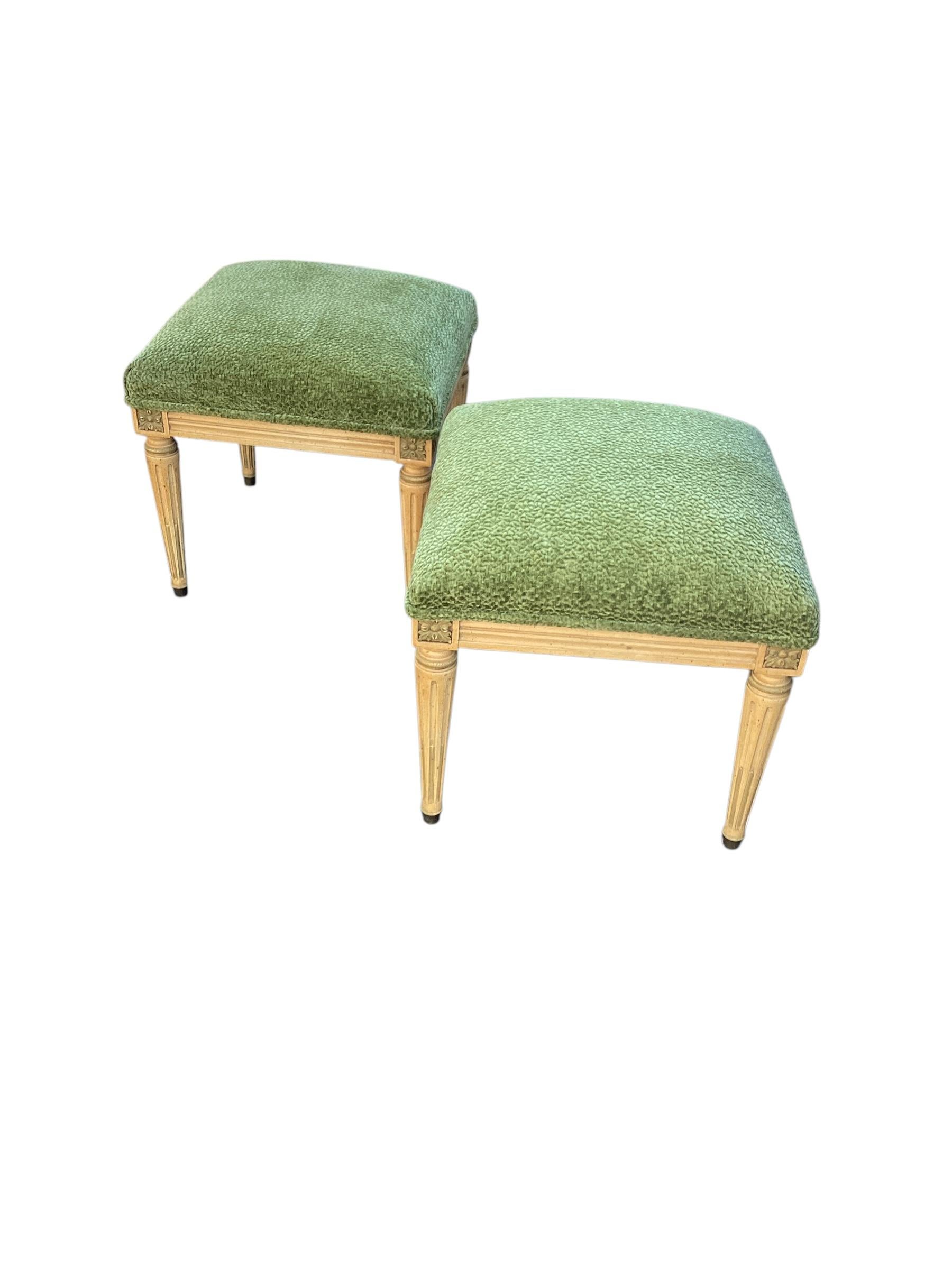 Paire de tabourets Louis XVI du milieu du siècle à la manière de Jansen. Jolie paire peinte en crème avec des accents verts. Elle a été récemment recouverte d'un tissu texturé vert et les pieds sculptés et cannelés se terminent par des capuchons en