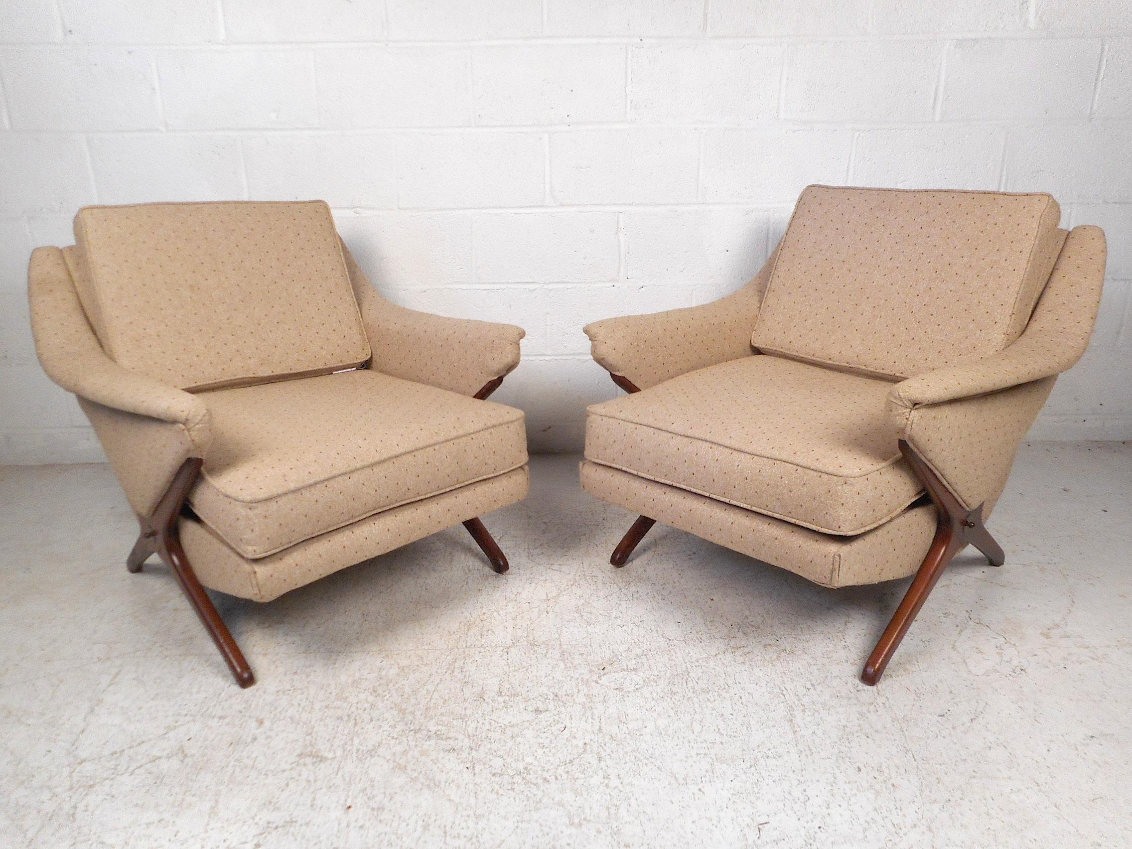 Stylish pair of lounge chairs. Sturdy sculpted walnut bases with decorative brass inserts, spacious seating area with comfortable cushioning covered in a beige textured upholstery. An impressive addition to any home, business, or office's modern