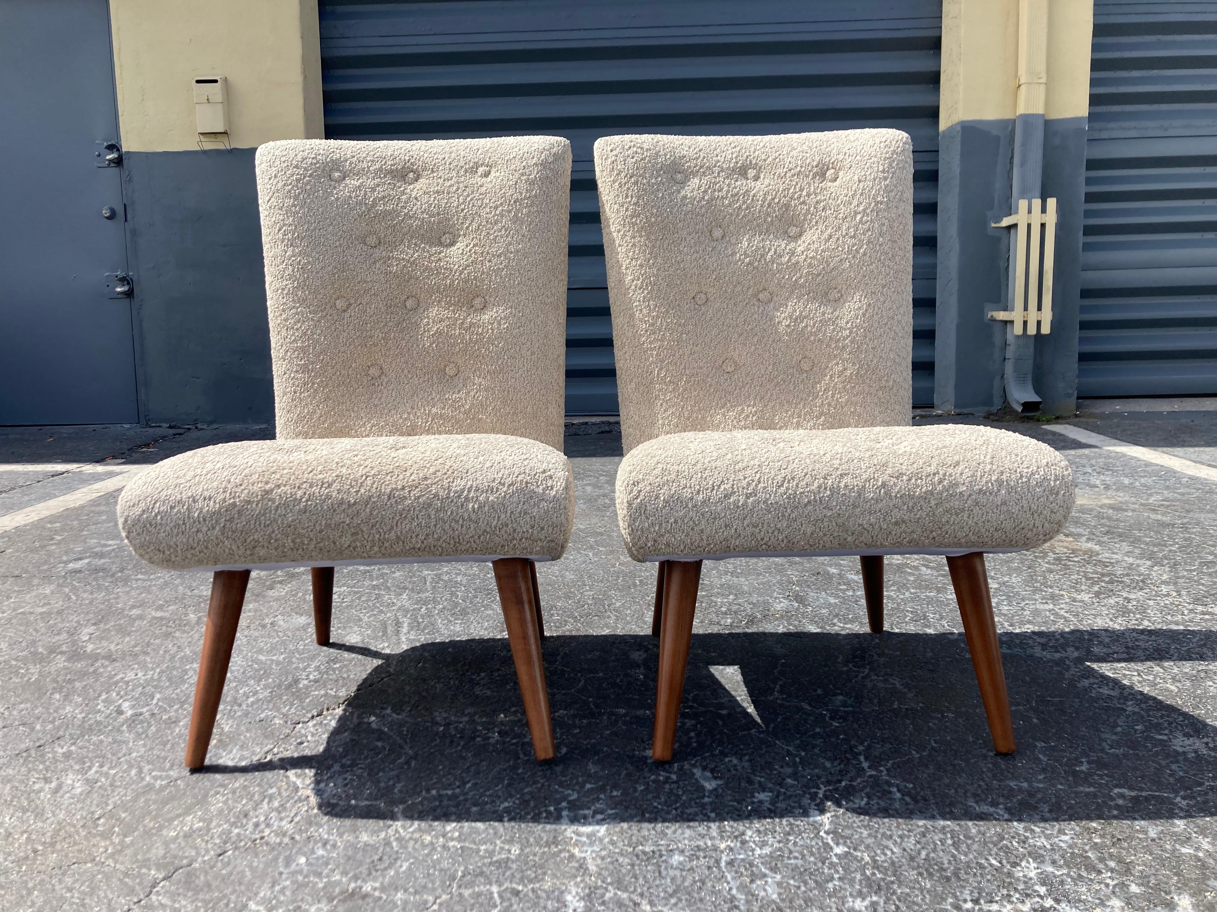 Pair of Mid-Century Modern lounge chairs. Recovered in sand colored boucle fabric, legs have a walnut finish. Each chair has twenty buttons. Ready for a new home.