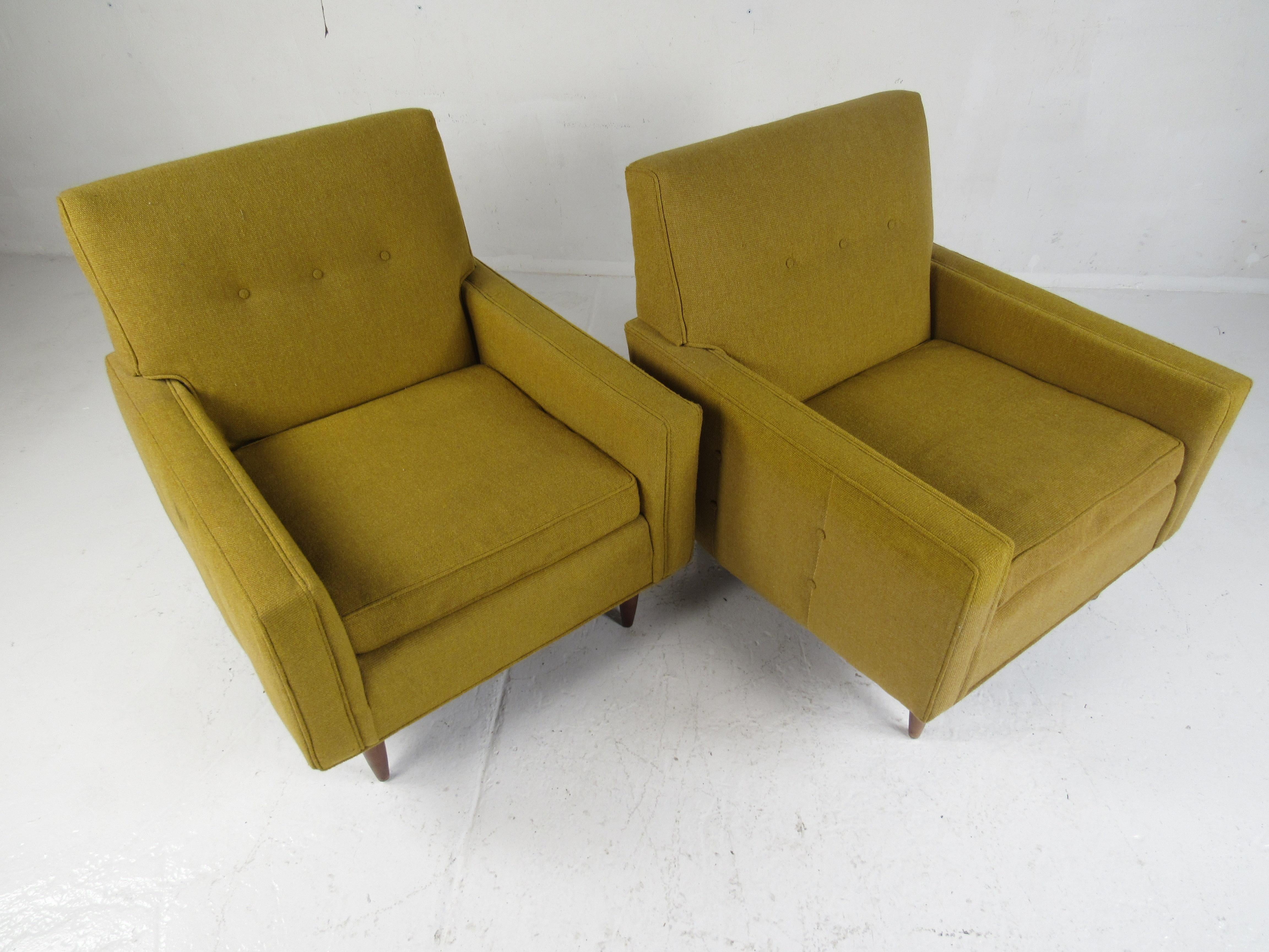 A comfortable and stylish pair of vintage modern club chairs by Rowe. Wonderful design with gently used green tufted upholstery and stubby walnut legs. This lovely pair of chairs make the perfect eye-catching addition to any seating arrangement.