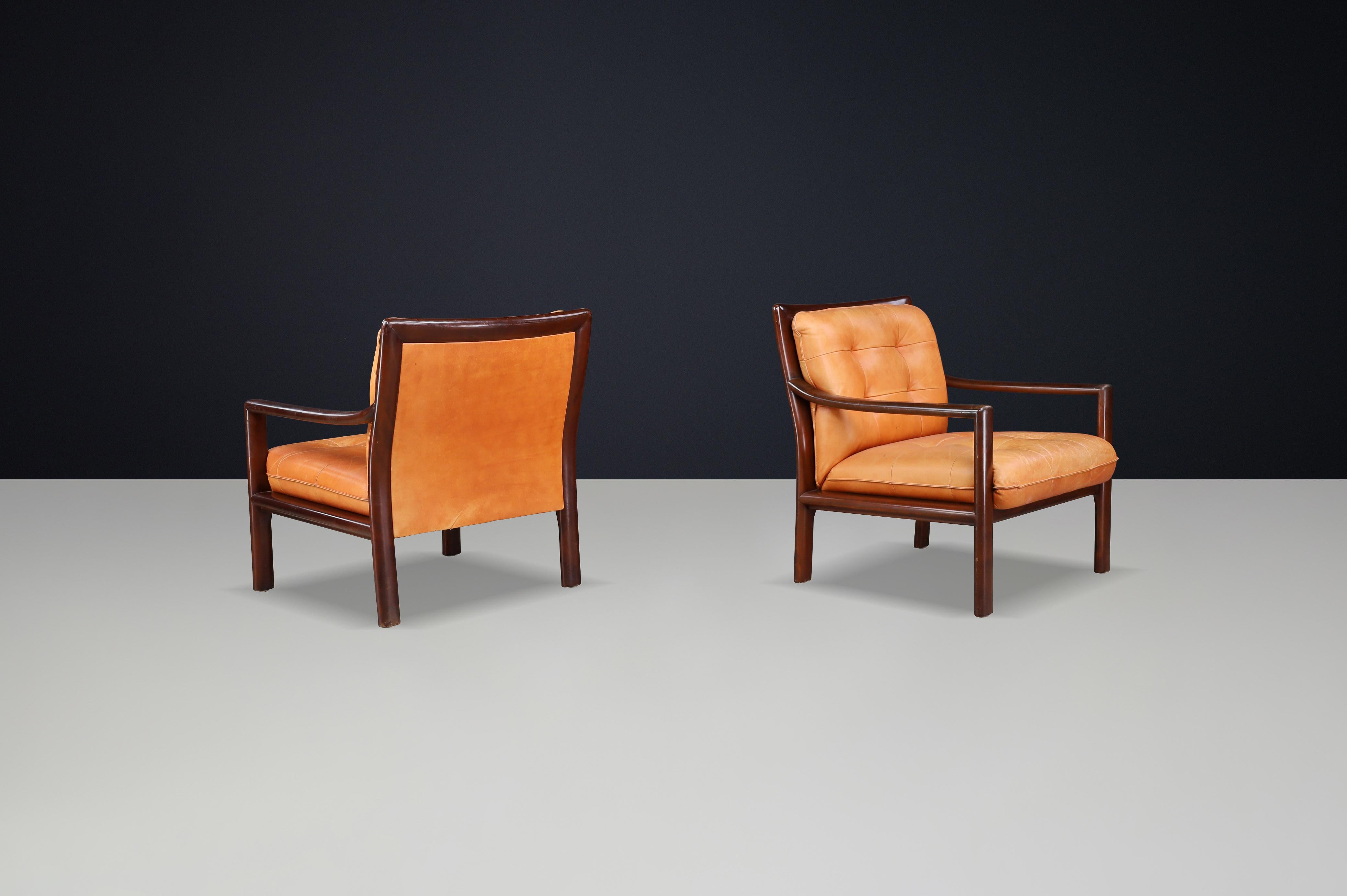 Mid-Century moderno Coppia di sedie da salotto di metà secolo in pelle cognac e legno duro tinto mogano in vendita