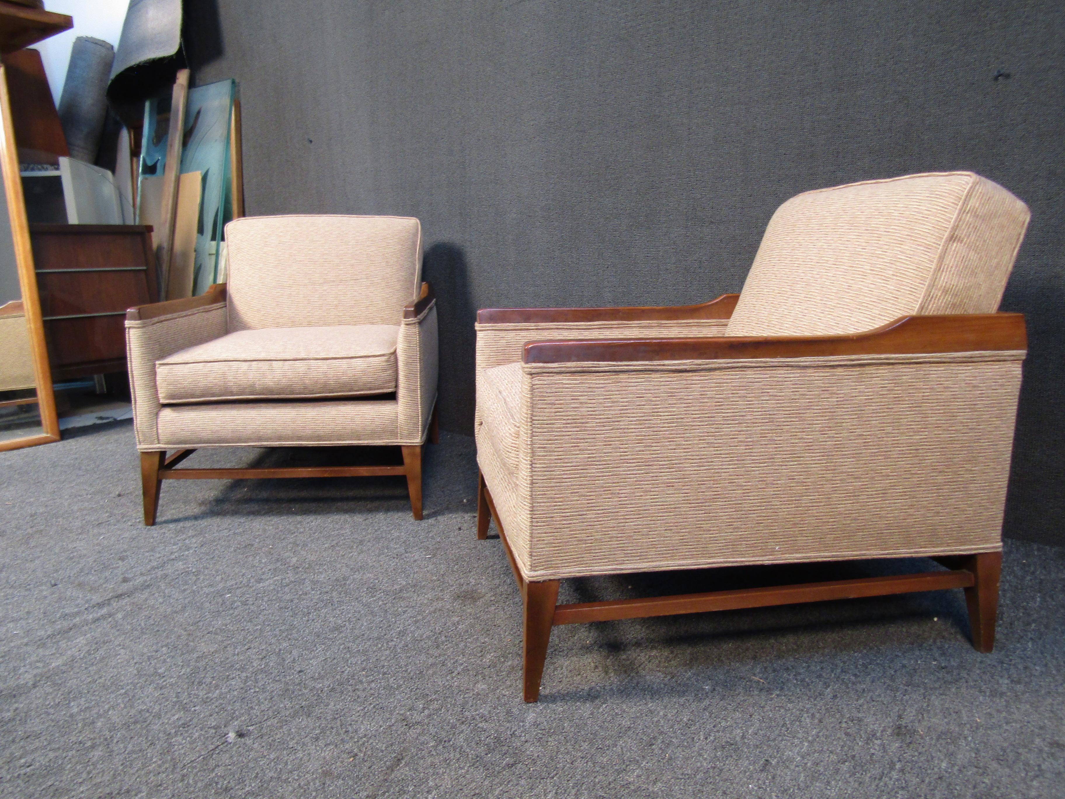 Pairing a warm beige upholstery with walnut frames, this vintage pair of lounge chairs are a versatile way to add Mid-Century Modern style to any home, office, or lobby. Their understated design are inspired by the style of Paul McCobb. Please