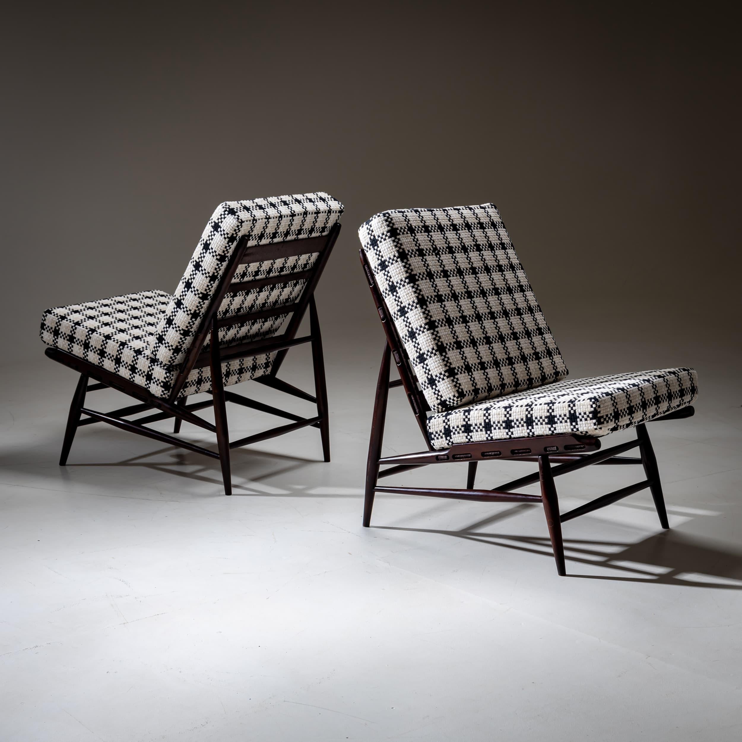A pair of Italian lounge chairs from the 1950s, featuring a dark-stained wooden frame with tapered legs and cross stretchers for added stability.

The chairs have been newly upholstered and covered in a high-quality, coarse-weave fabric with a bold