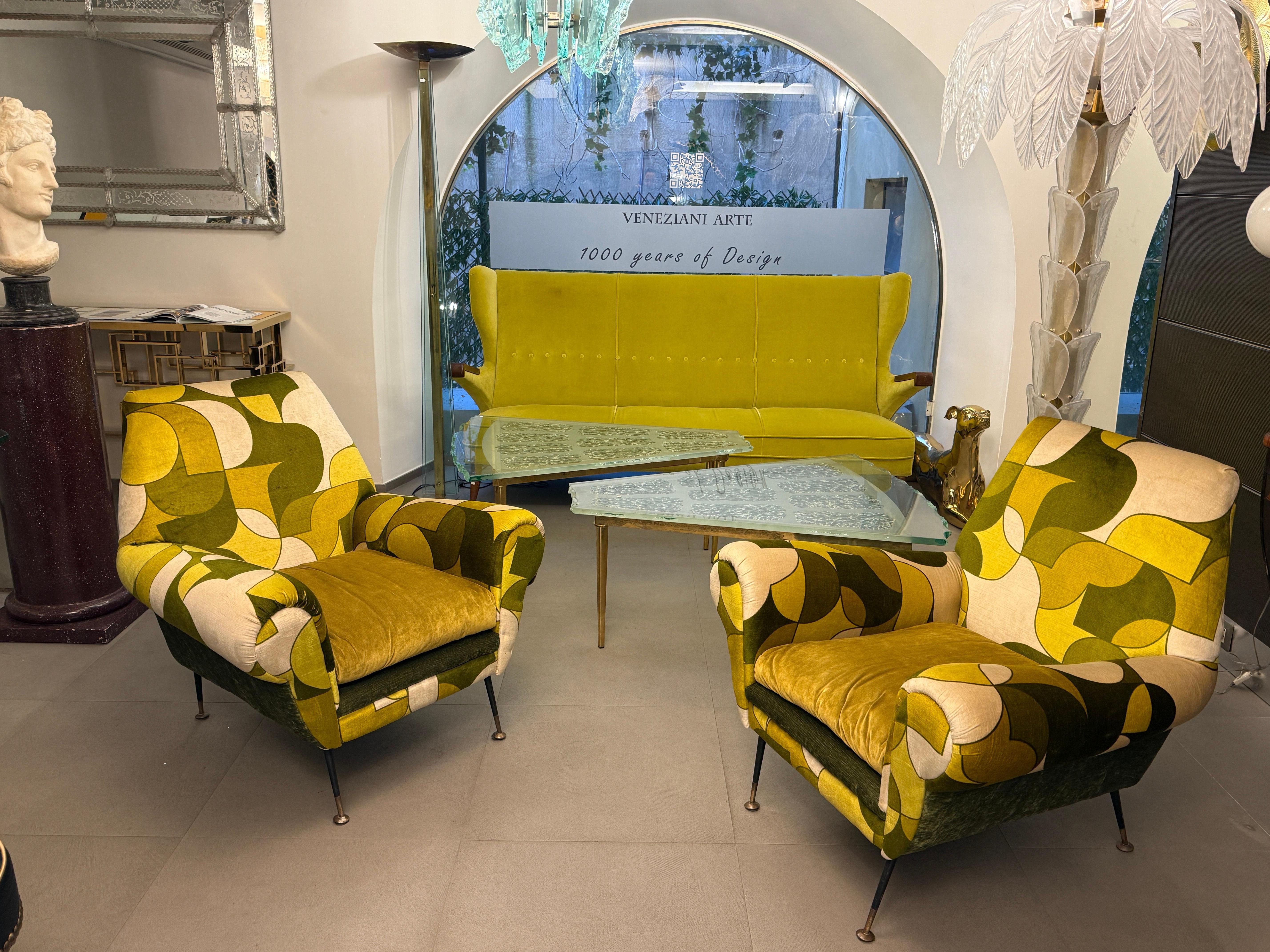 Very comfortable pair of armchairs with scrolled hand holds by Gigi Radice for Minotti. 
 Soft and beautiful original vintage multicolor velvet upholstery. The conical legs are black enameled steel encased in brass-plated feet in original condition.