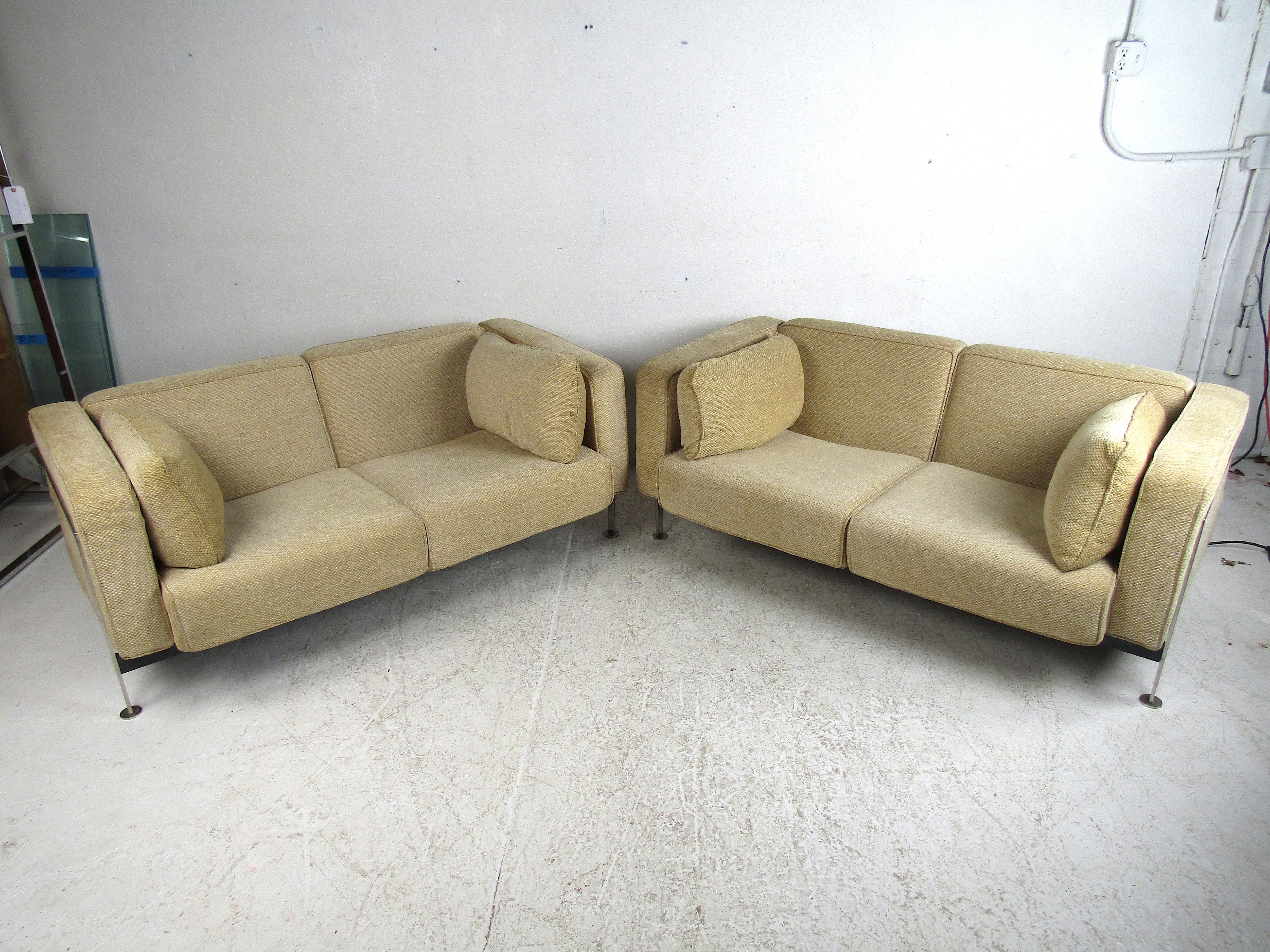 Great pair of Mid-Century Modern loveseats designed by Robert Haussmann. Quality construction with a sturdy polished steel frame spanning the sides and back of the pieces. Upholstered in a vintage beige fabric that has held up very well. This pair