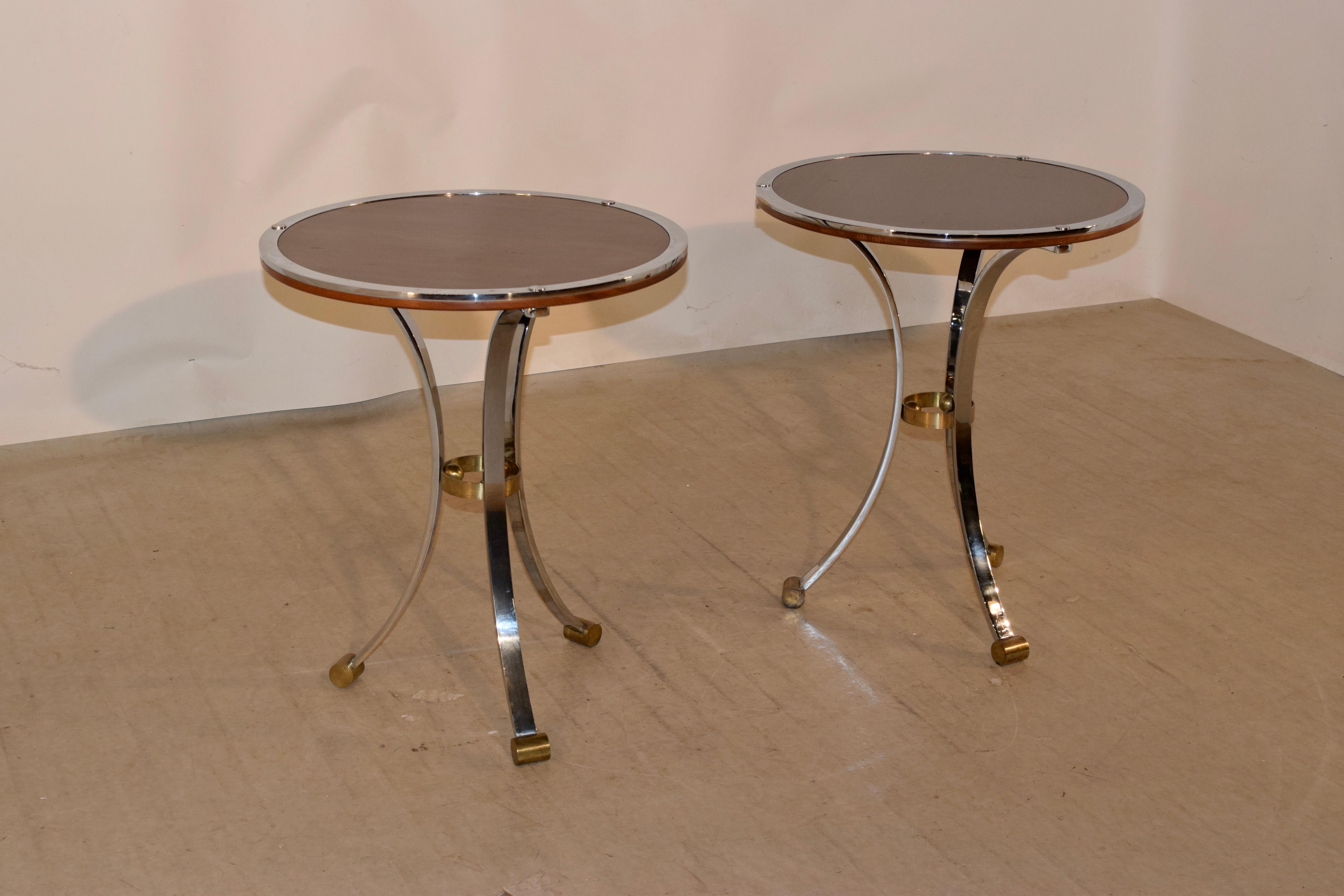 Pair of Mid-Century Modern side tables from England with mahogany tops, banded in chrome. They are supported on chrome legs joined by brass circles and ending in brass feet.