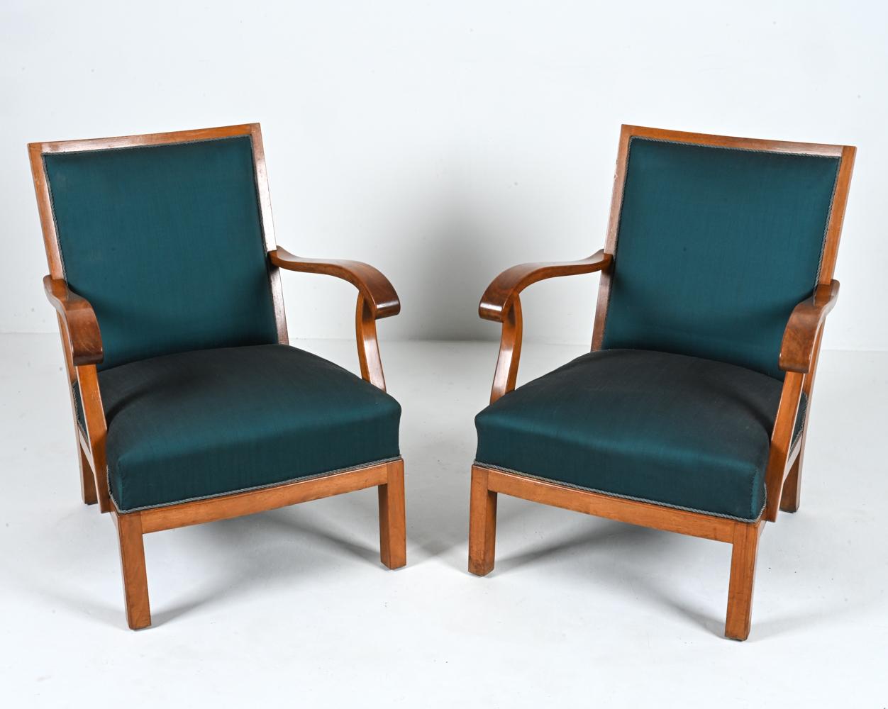Introducing a rare and exquisite pair of open-arm lounge chairs designed by the renowned Danish craftsman, Erik Wørts, and meticulously produced in Denmark during the 1950's. These exceptional chairs showcase the timeless beauty of mahogany frames,