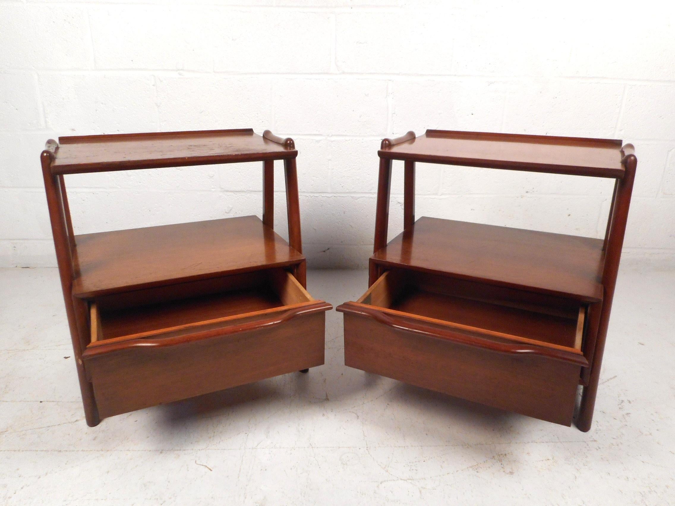 This unique pair of midcentury nightstands feature a sturdy mahogany construction certified by the Mahogany Association Inc. ensuring the authenticity of the wood. Interestingly contoured frames on either side secure the drawer's casing and offer a