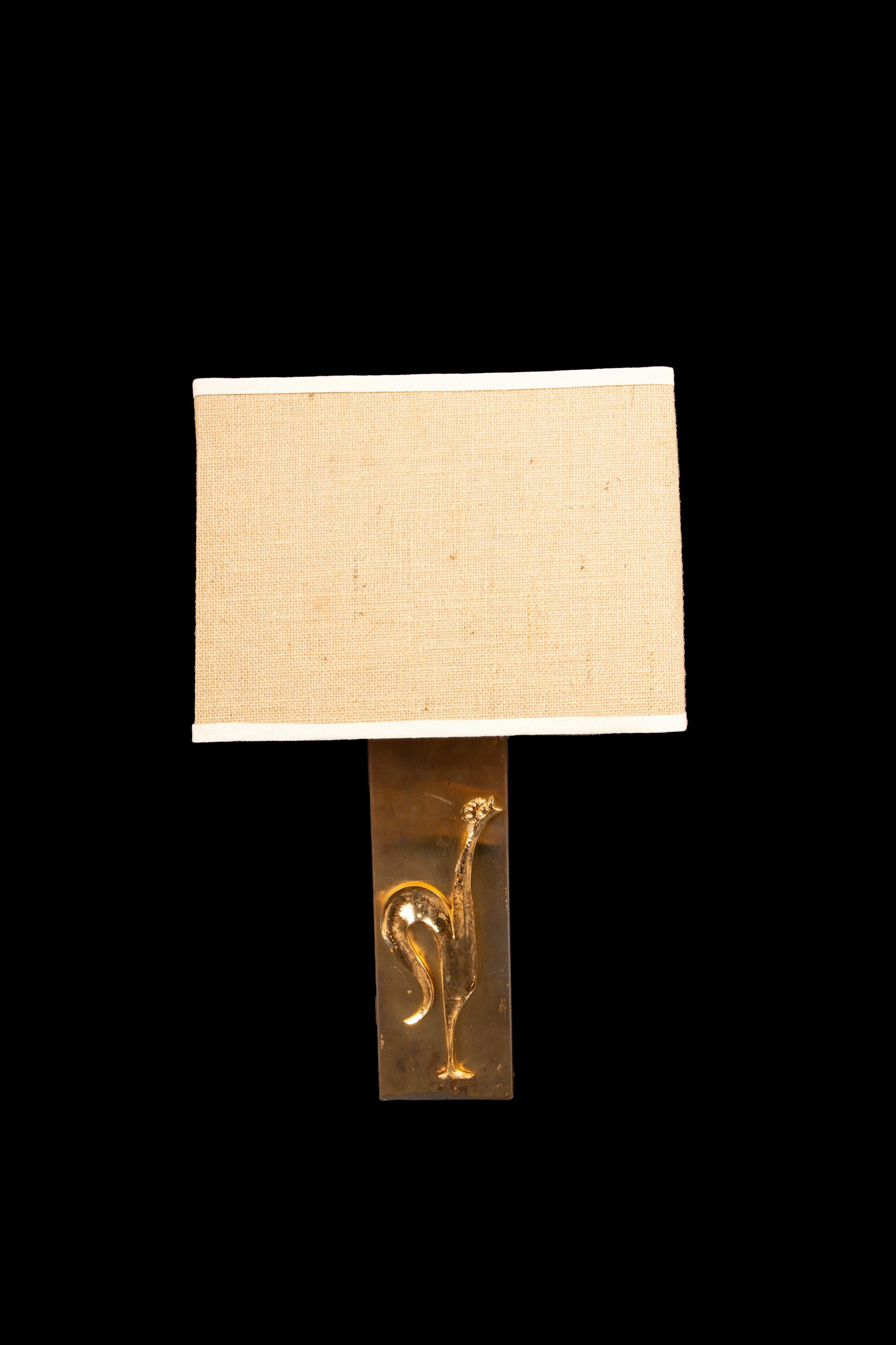 Cette élégante paire de lampes de table à coq en laiton doré, datant du milieu du XXe siècle, illustre le mélange iconique de design moderniste et d'art sculptural de la marque. Chaque lampe présente un panneau de laiton élégant avec un coq stylisé
