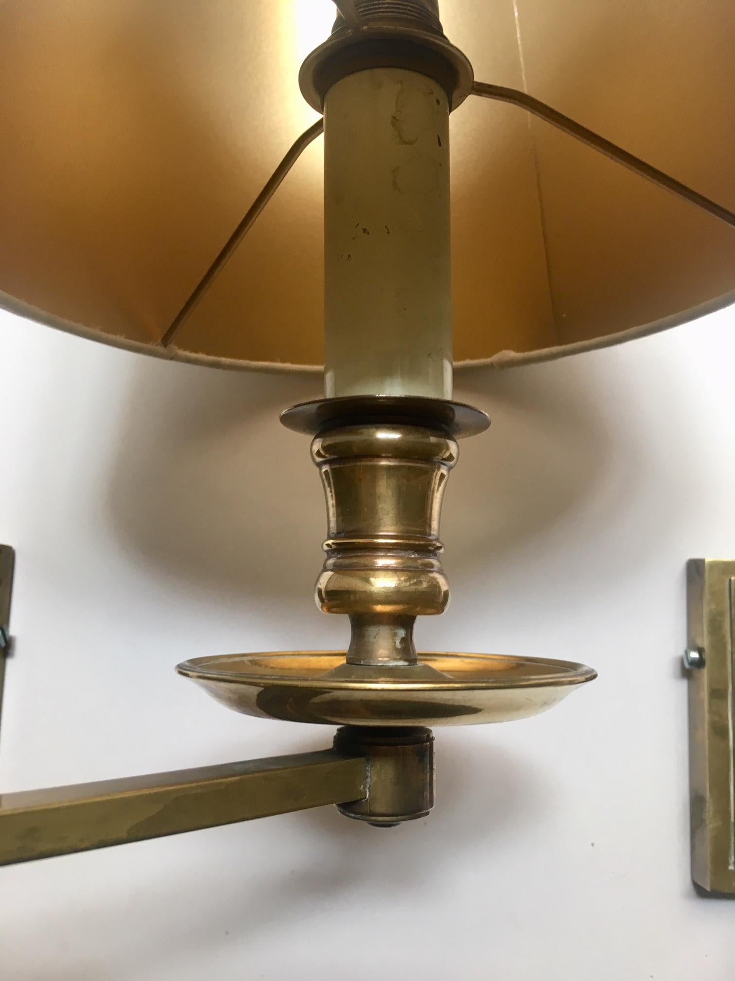 Pair of adjustable swing arms wall sconces, made of brass with age finish.