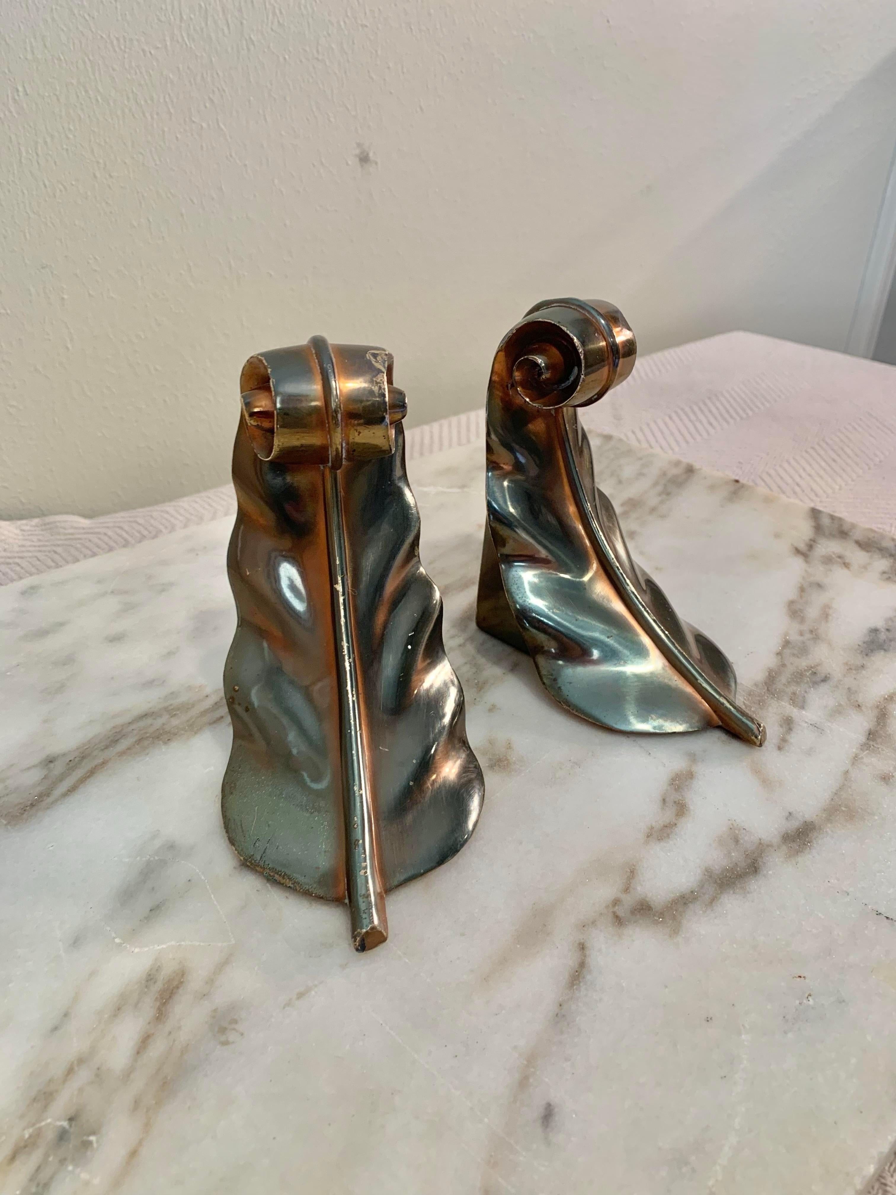 Solid and sturdy, this Pair of Mid Century Modern Aged Brass Acanthus Leaf Scroll Bookends would be a beautiful addition to your home office or library. The base off each bookend is covered in felt to protect the furniture they are placed on. Given