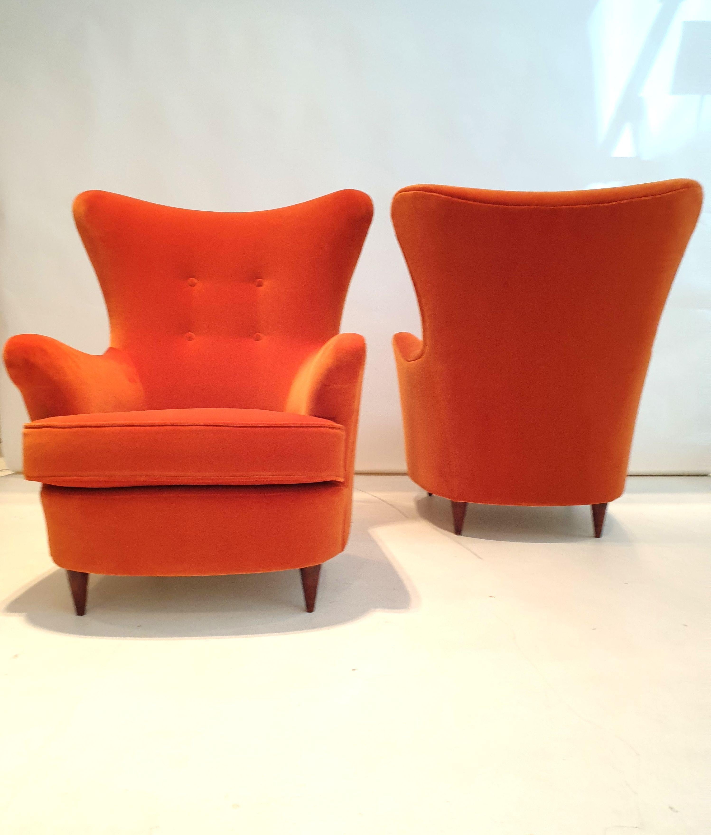 Pair of stylized armchairs with polished wooden feet, reupholstered in burnt orange velvet.