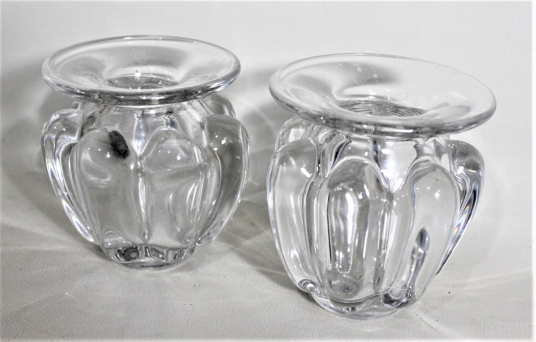 This pair of clear art glass vases were made by Art Vannes of France in approximately 1970 in a Mid-Century Modern style. These squat and heavy vases have thick ribbed sides and a large round flat rim. Each vase is signed with an acid etched makers