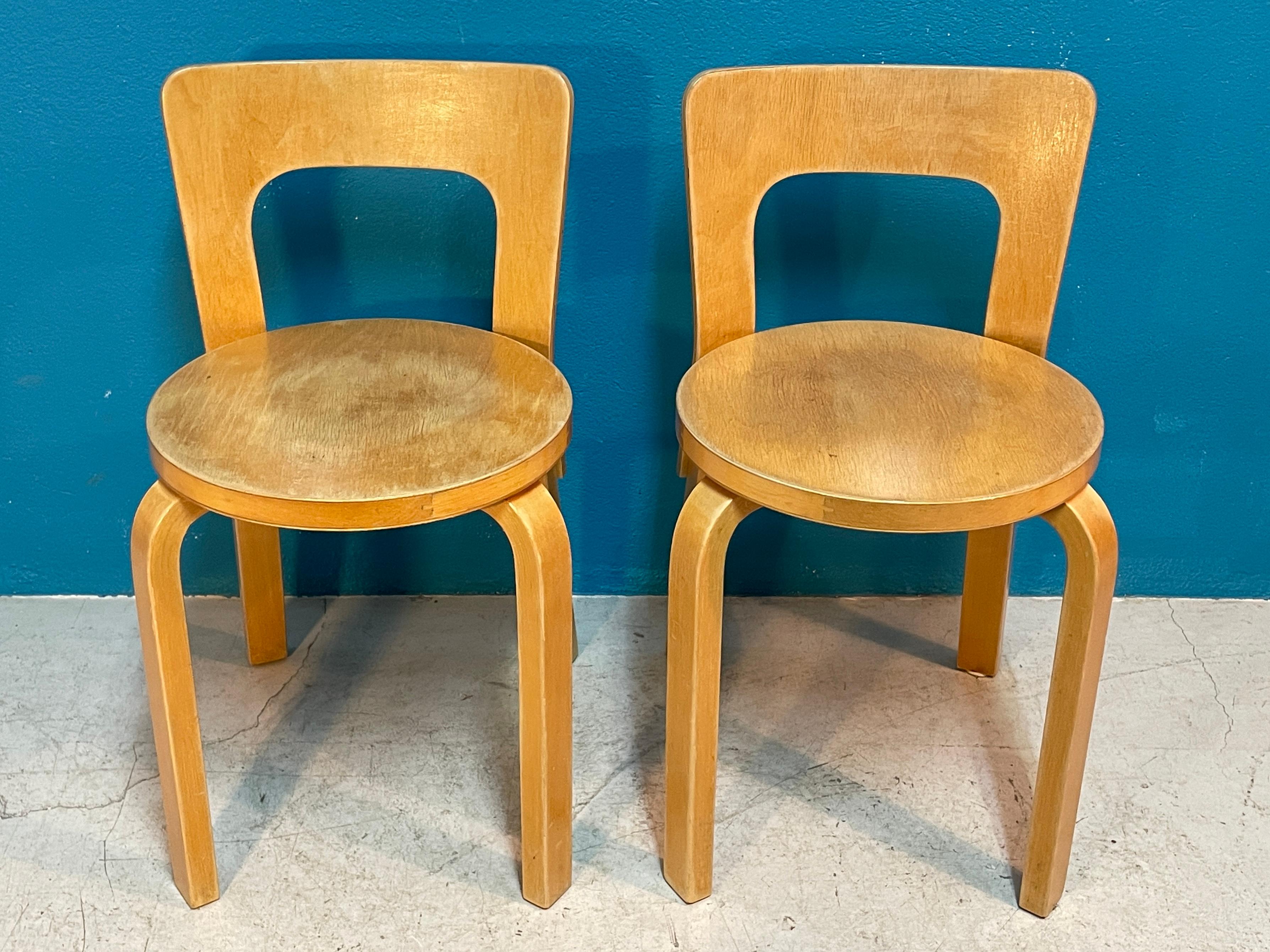 Nice pair of Alvar Aalto Model 65 dining chairs by Artek Finland, circa 1950s. Classic Aalto-Design furniture, the round seat is supported by four L-legs. 
Alvar Aalto designed this model in 1935.

Heavily Patinated chairs but still sturdy chairs