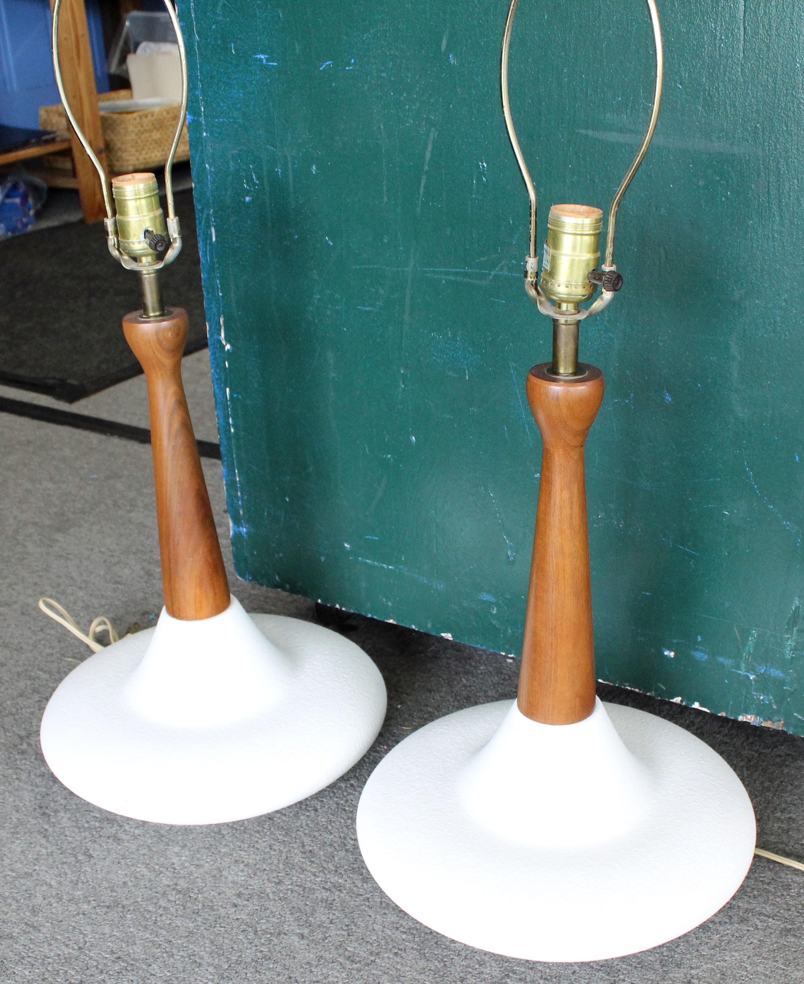 Offered is a retro pair of Mid-Century Modern table lamps, made with walnut and a white textured pottery bottom. They are in excellent, working condition, showing normal wear. They are not signed. Really cool lighting for any room.