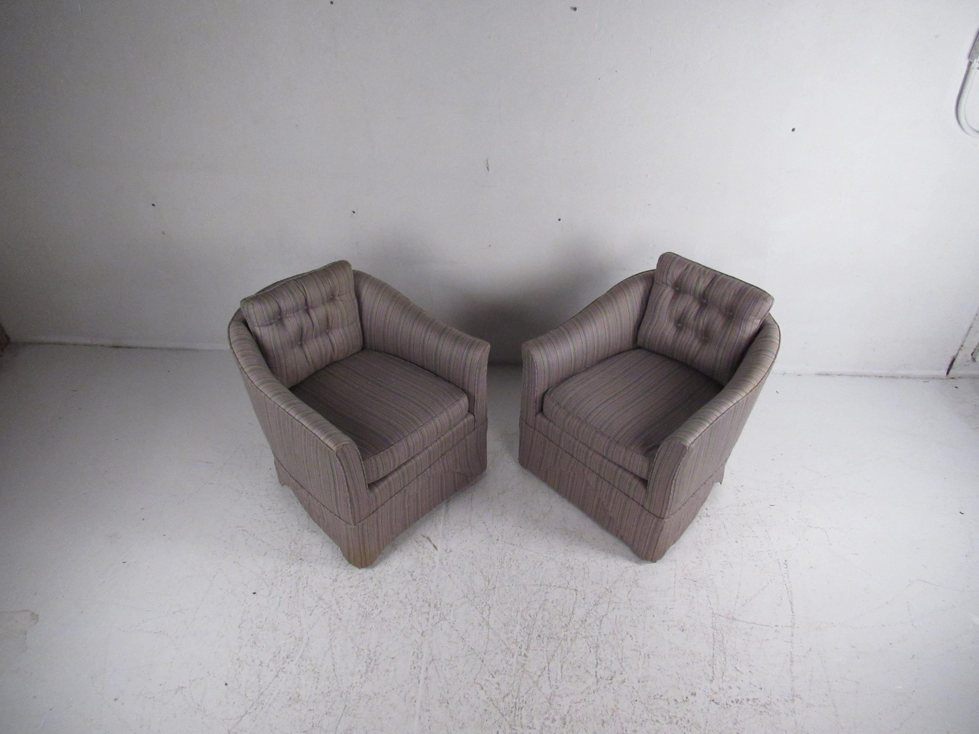 This gorgeous pair of vintage modern lounge chairs feature two overstuffed removable cushions and plush upholstery. A unique draping fabric along the base and curved arm rests add to the allure. This stylish pair with tufted backrests sit on top of