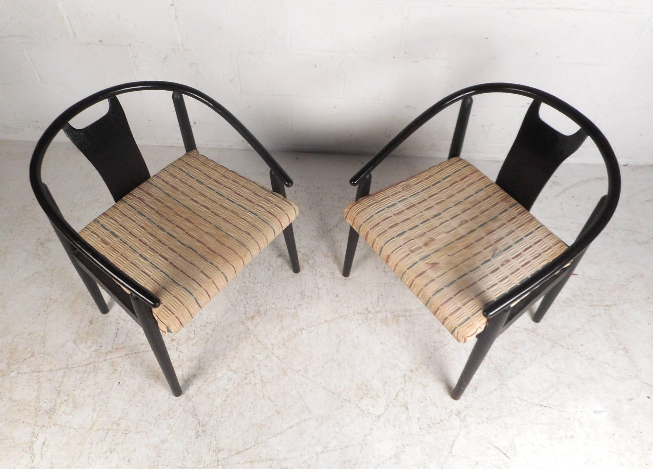 Amazing pair of vintage modern dining chairs with sloping arm rests and a black painted wood frame. Unique design has a barrel back rest with a sculpted centre support and thick padded seating for maximum comfort. The sturdy cylindrical frame with