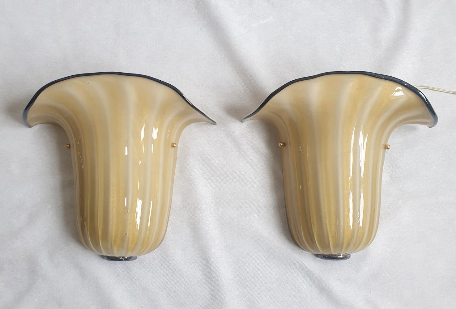 Pair of tulip flower shape Murano glass wall sconces, attributed to Seguso, Italy, circa 1970.
The Mid-Century Modern Murano sconces are translucent, in a beige color, with gold leaf inclusions and a black line accent.
They have brass mounts and