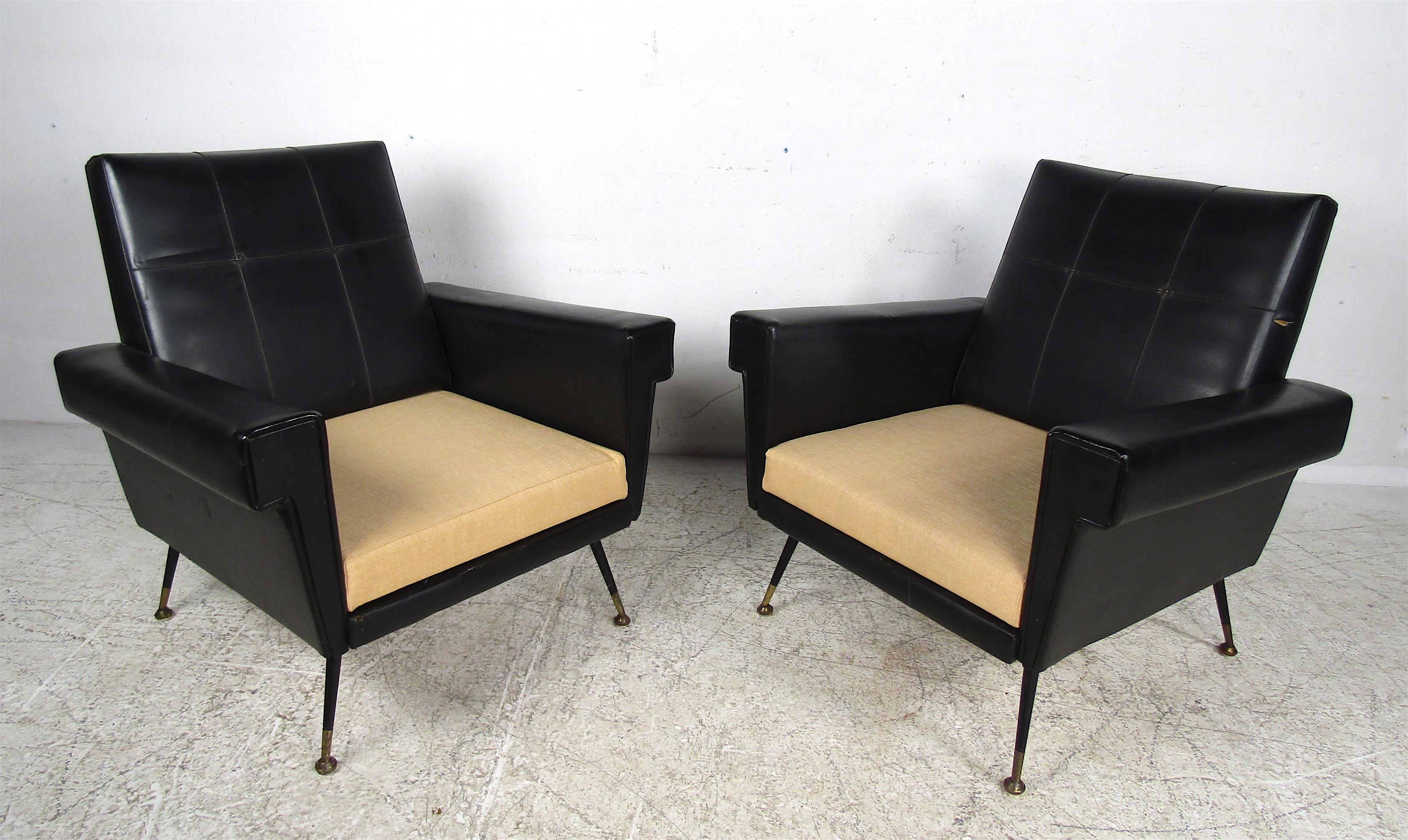 A stunning pair of armchairs with beige/yellow colored cushions that complement the black vinyl upholstery. The winged armrests, splayed legs, and angled backrest ensure optimal comfort without sacrificing style. Perfect for the home, business, or