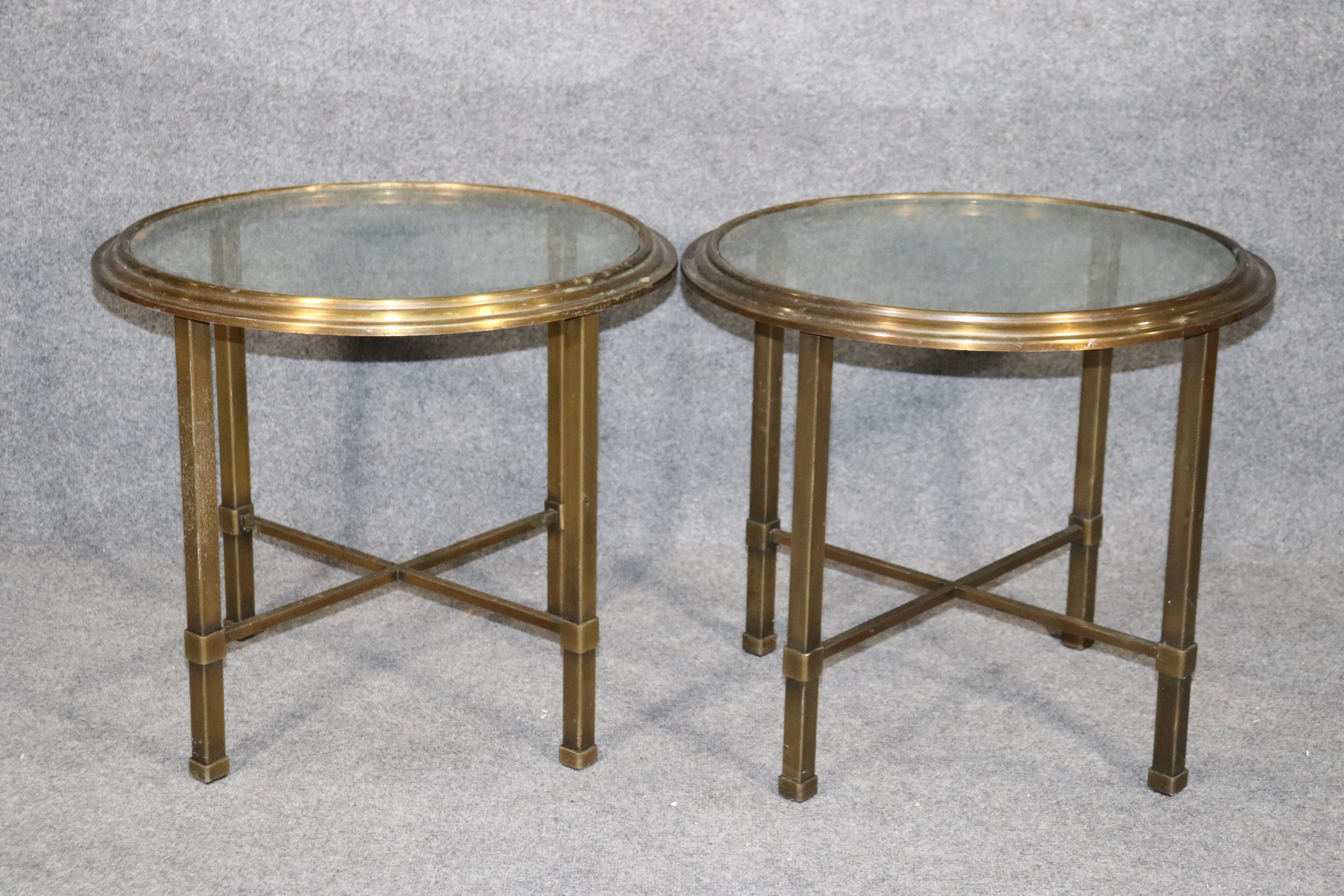 This is a rare pair of Mastercraft (attributed) brass and glass end tables. The tables are vintage and have a beautiful almost Art Deco design but are more accurately described as mid-century modern. The tables have their original patina and can be