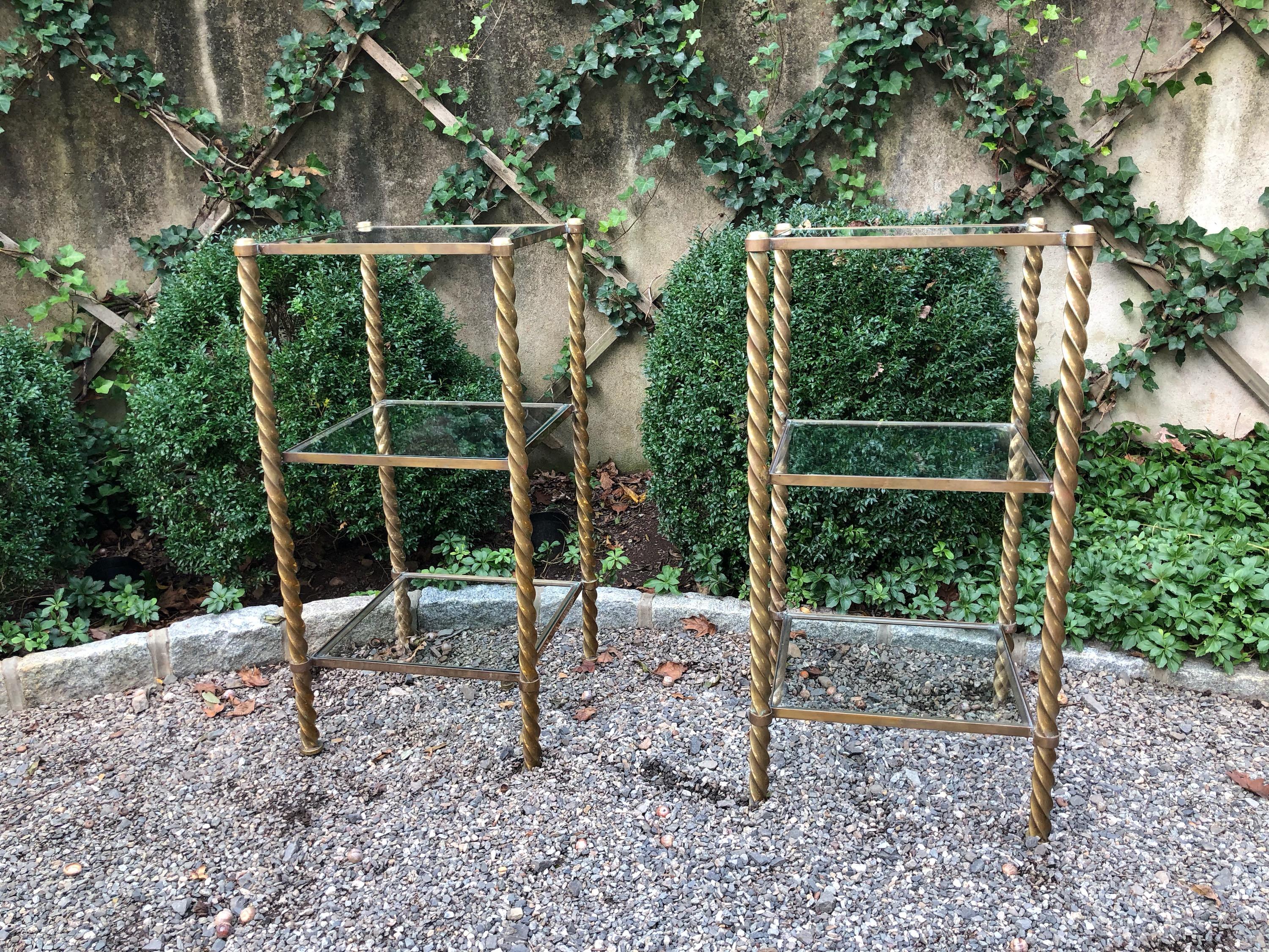 Pair of very stylish Mid-Century Modern brass and glass 3-tiered étagères having shelves with inset glass flanked by barley twist supports. They are quite heavy as the brass is thick and substantial.

Distance from floor to first shelf is 8””; first